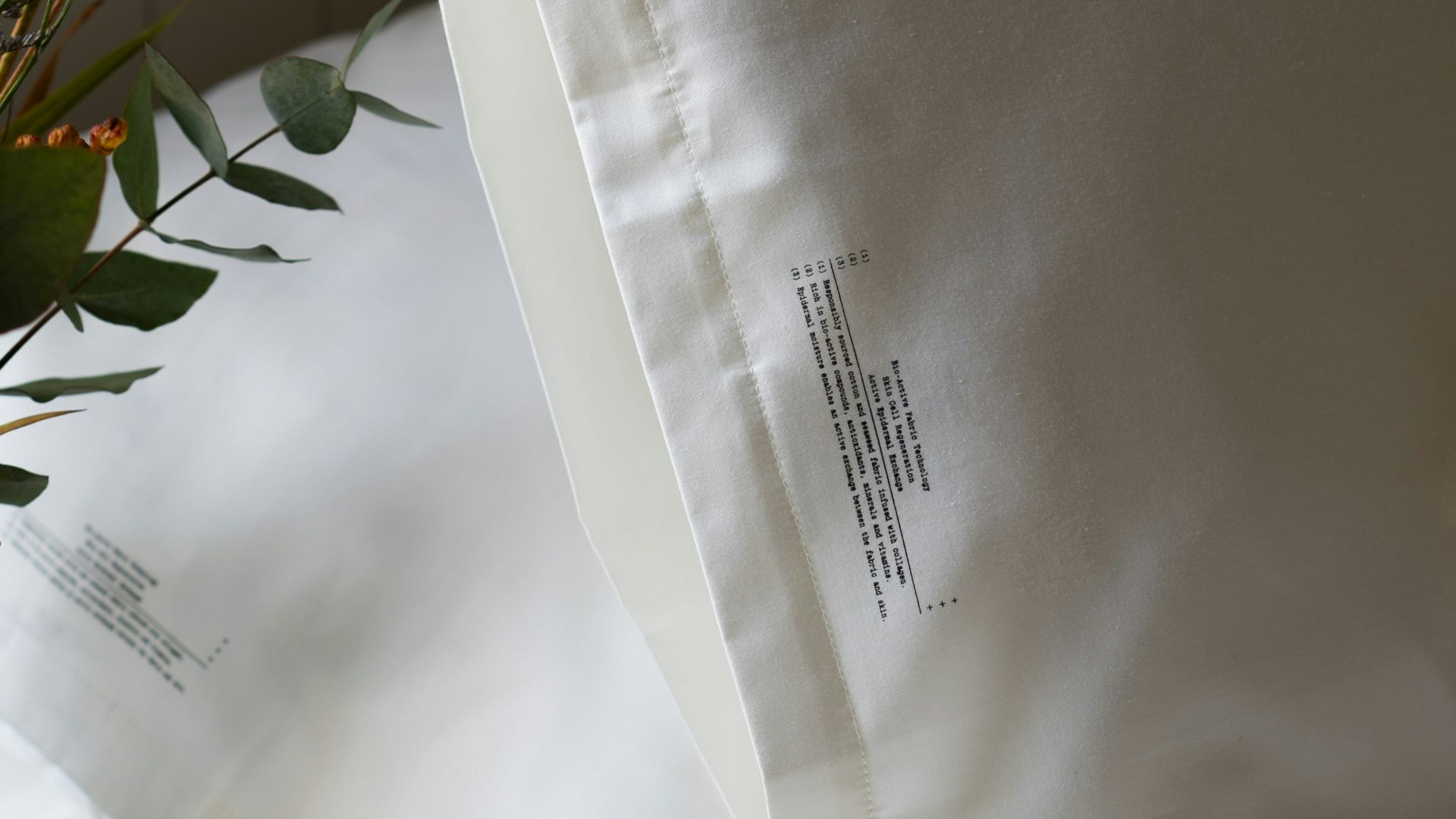 a close up of a bed with white sheets and pillows