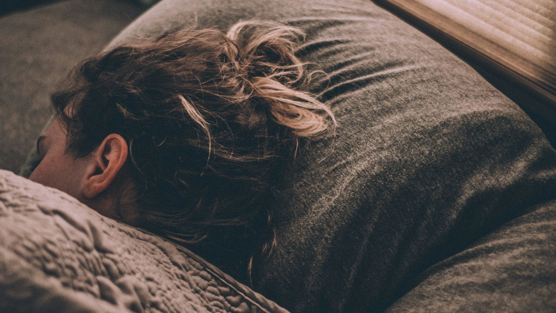 woman sleeping on bed under blankets