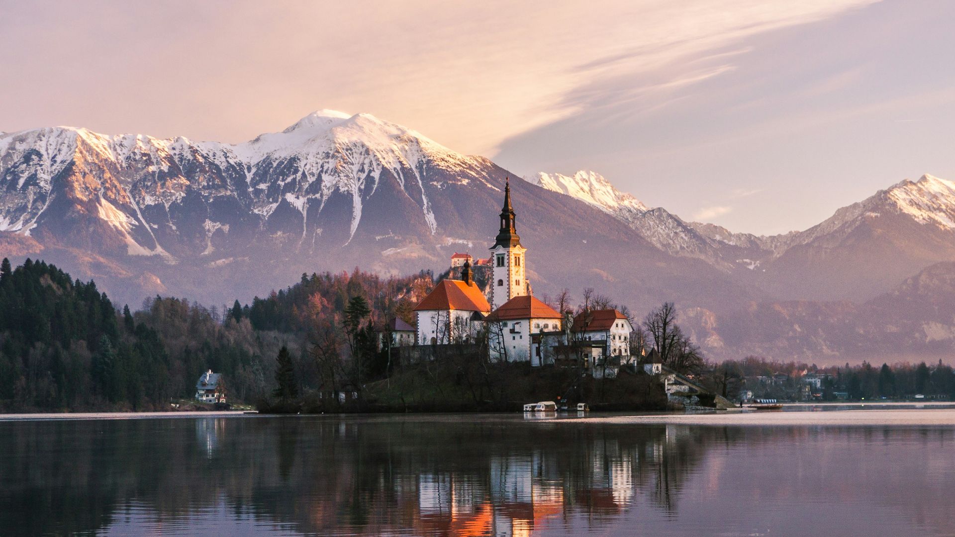 brown and white concrete building near lake and mountain under white clouds during daytime