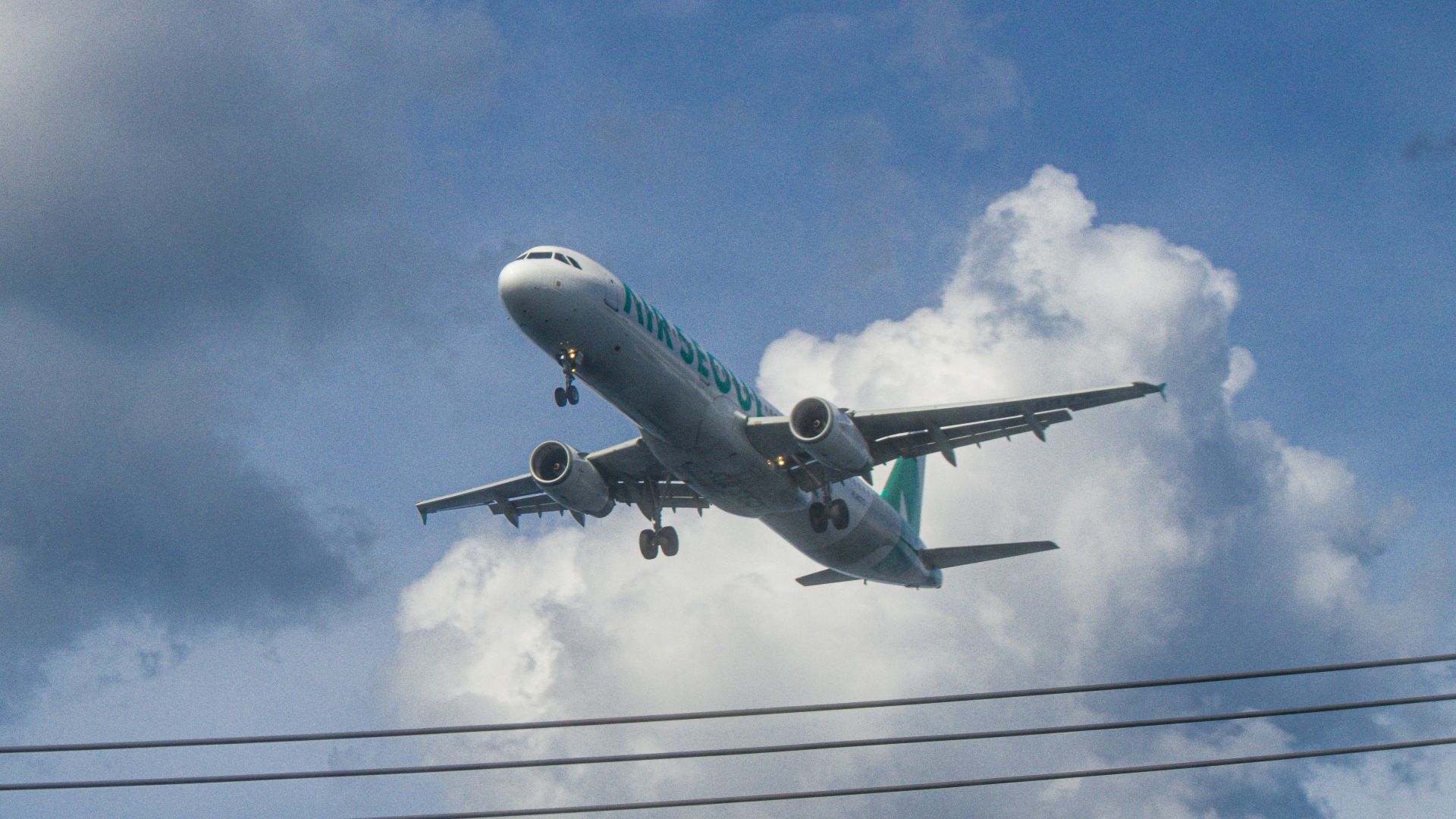 Airplane flying through cloudy blue sky