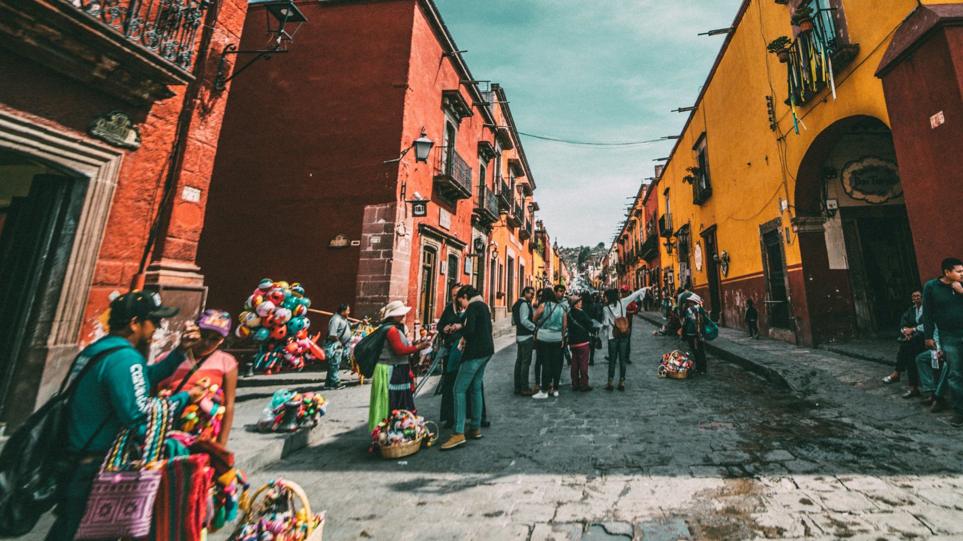 people standing on corner road near concrete buildings during daytime