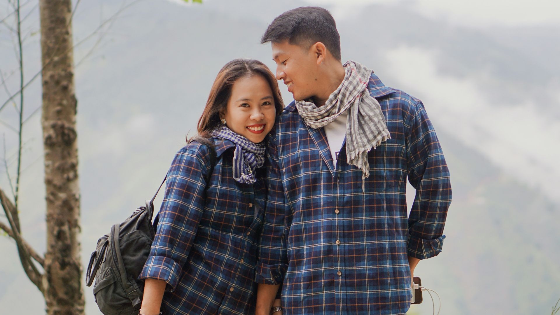man in blue and white plaid dress shirt hugging woman in blue and white plaid dress