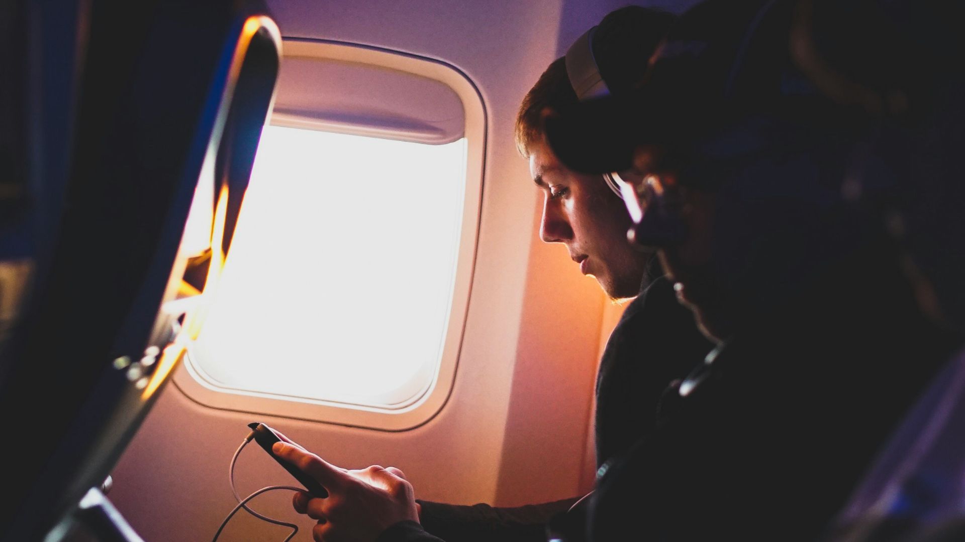 photo of three people listening to music inside airplane
