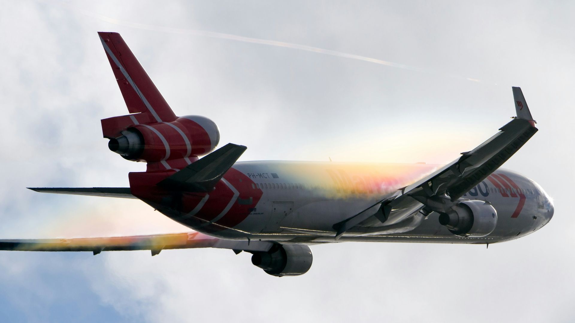 white and red airplane under white clouds during daytime