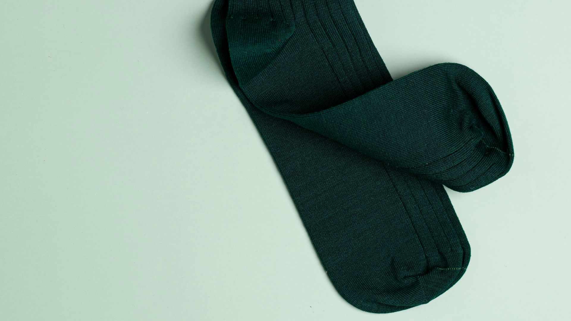 a pair of green socks laying on top of a white surface