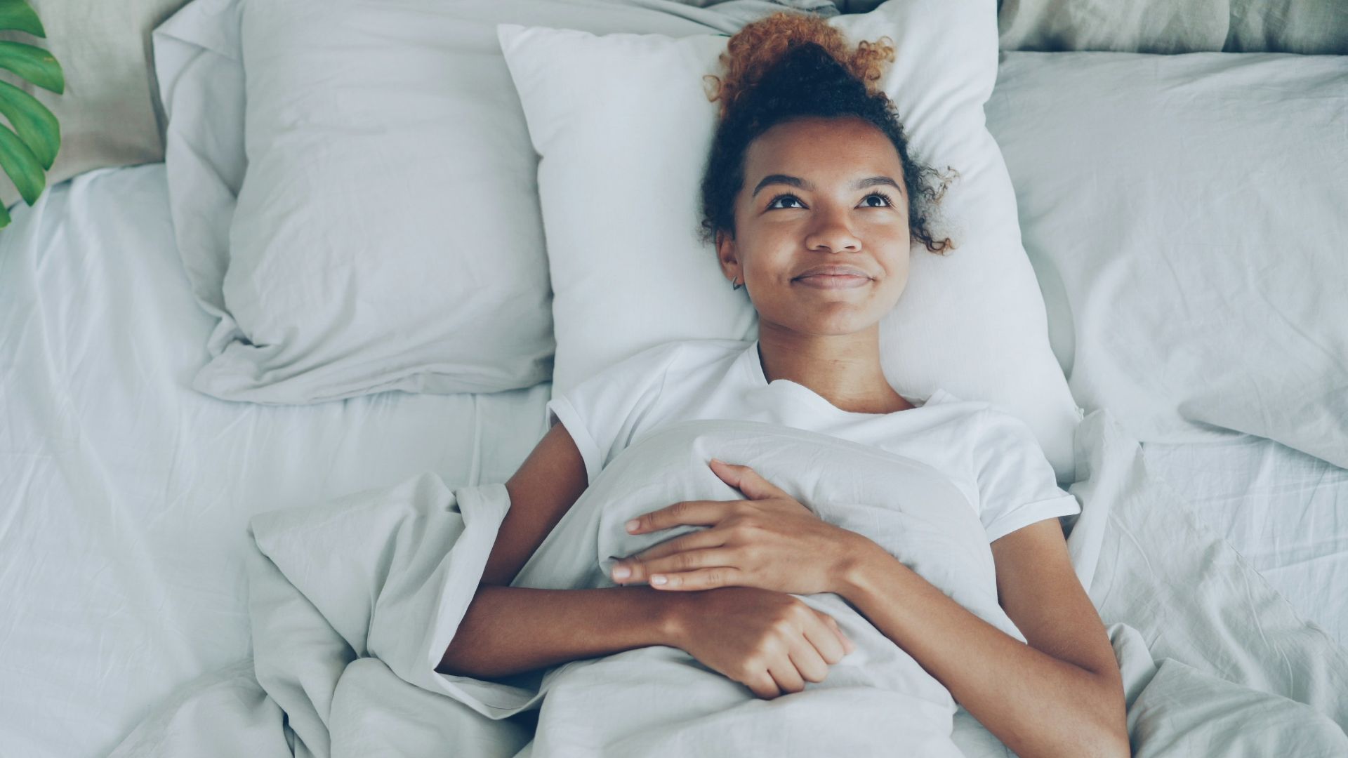 Young woman lying in a white bed