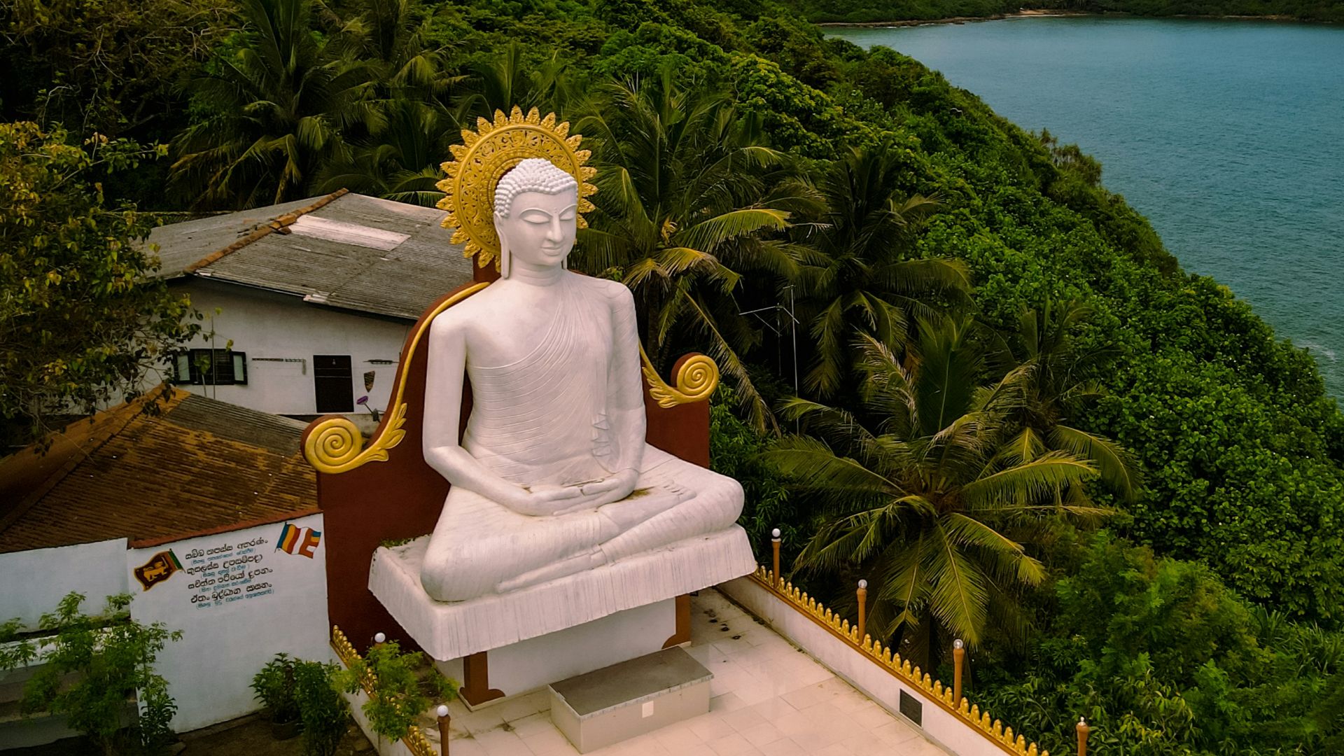 a statue of a person sitting on a bench by a body of water