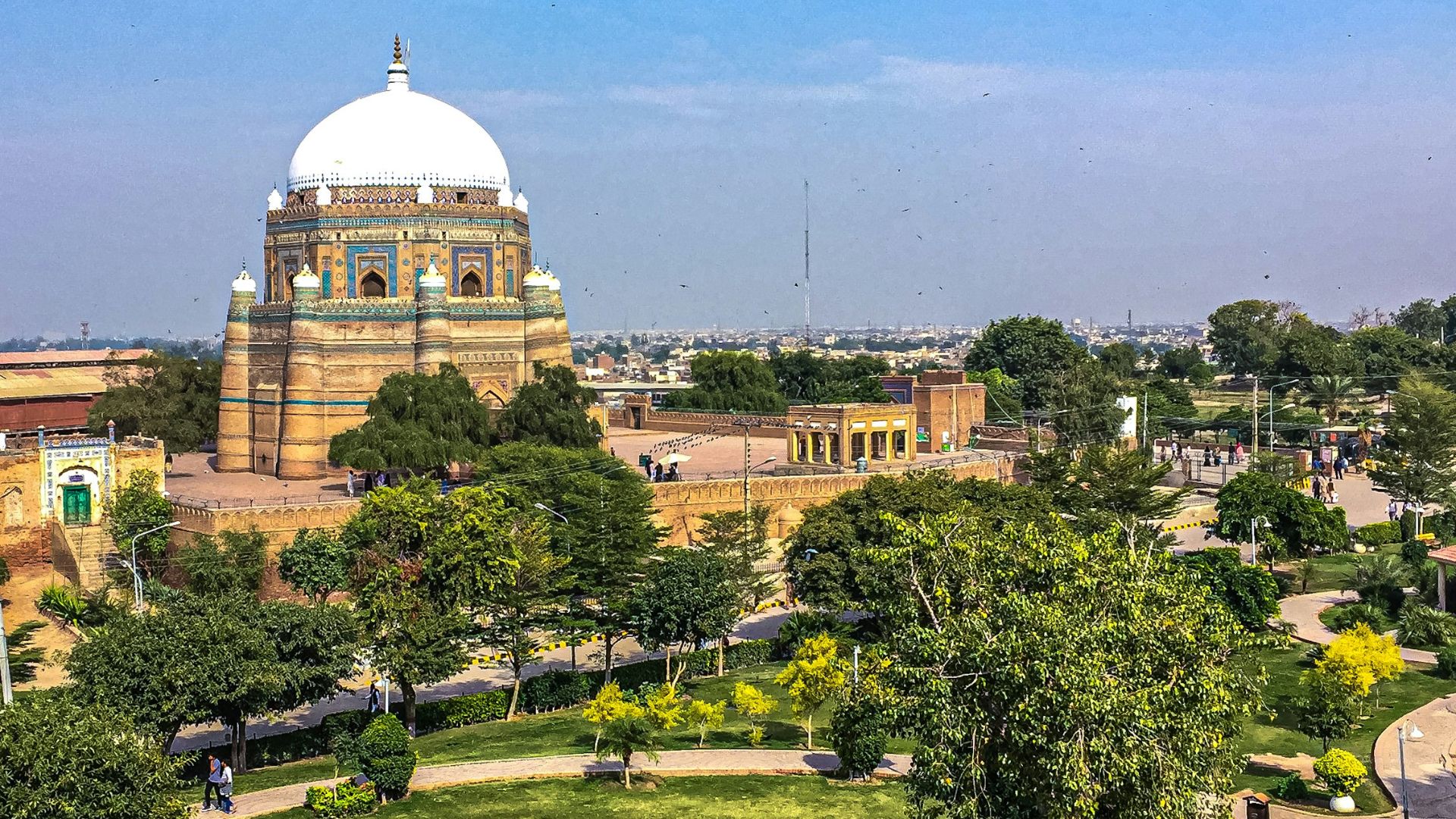 green trees near brown concrete building under blue sky during daytime