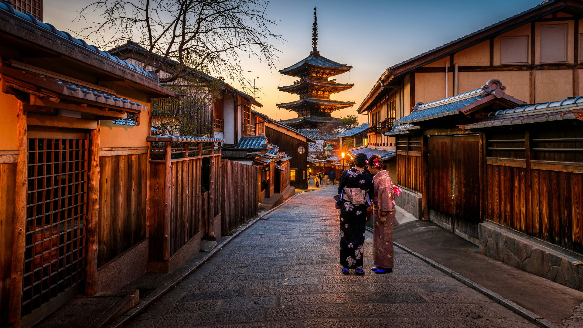 two women in purple and pink kimono standing on street