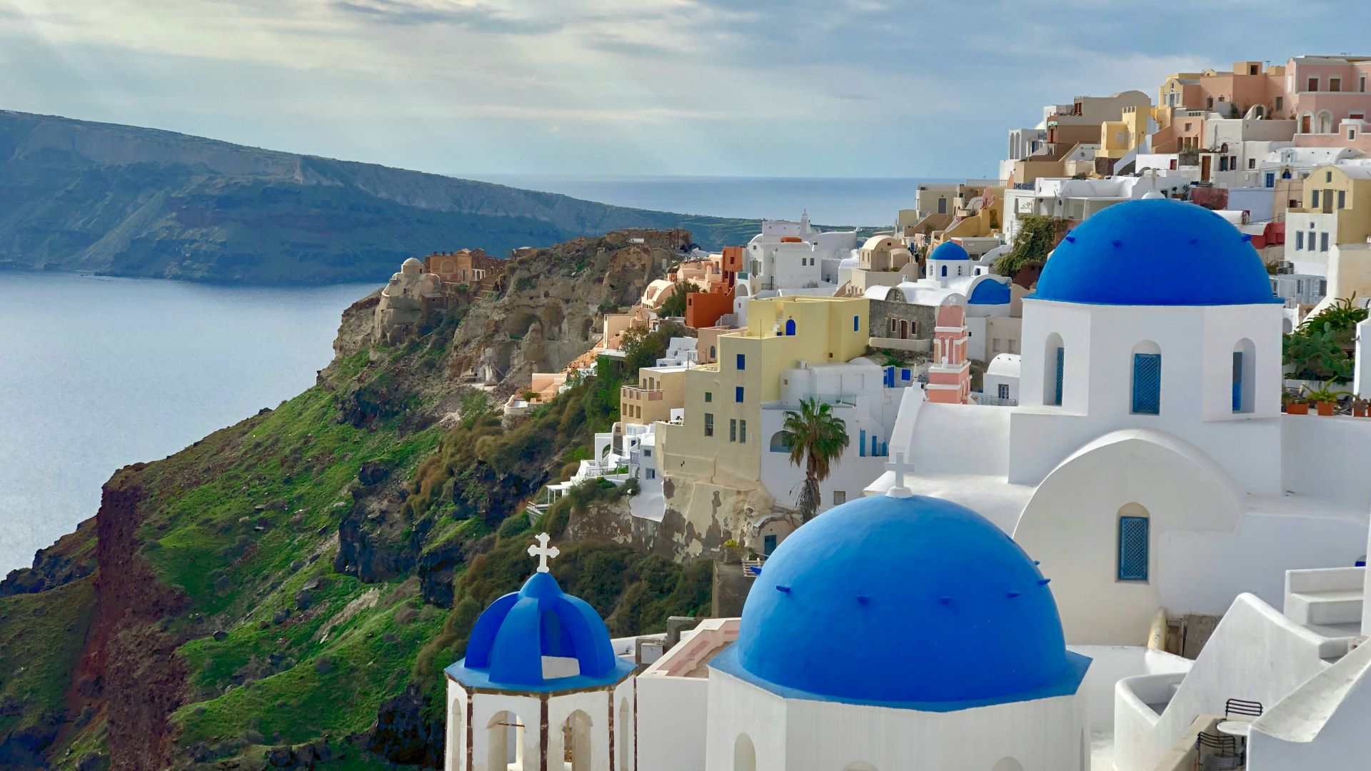 white and blue concrete building near green mountain under white clouds during daytime