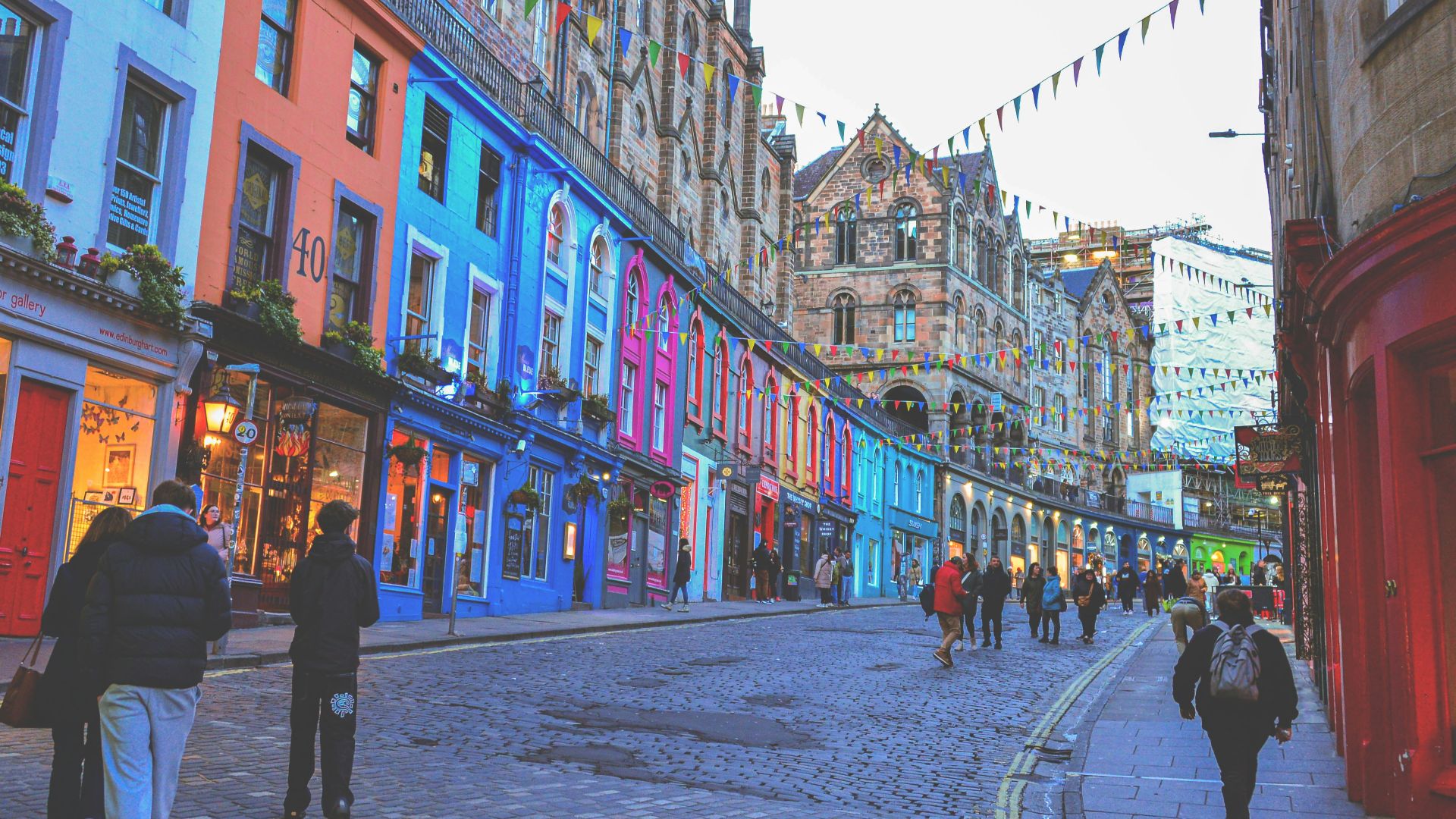 Colorful buildings line a street with people walking.