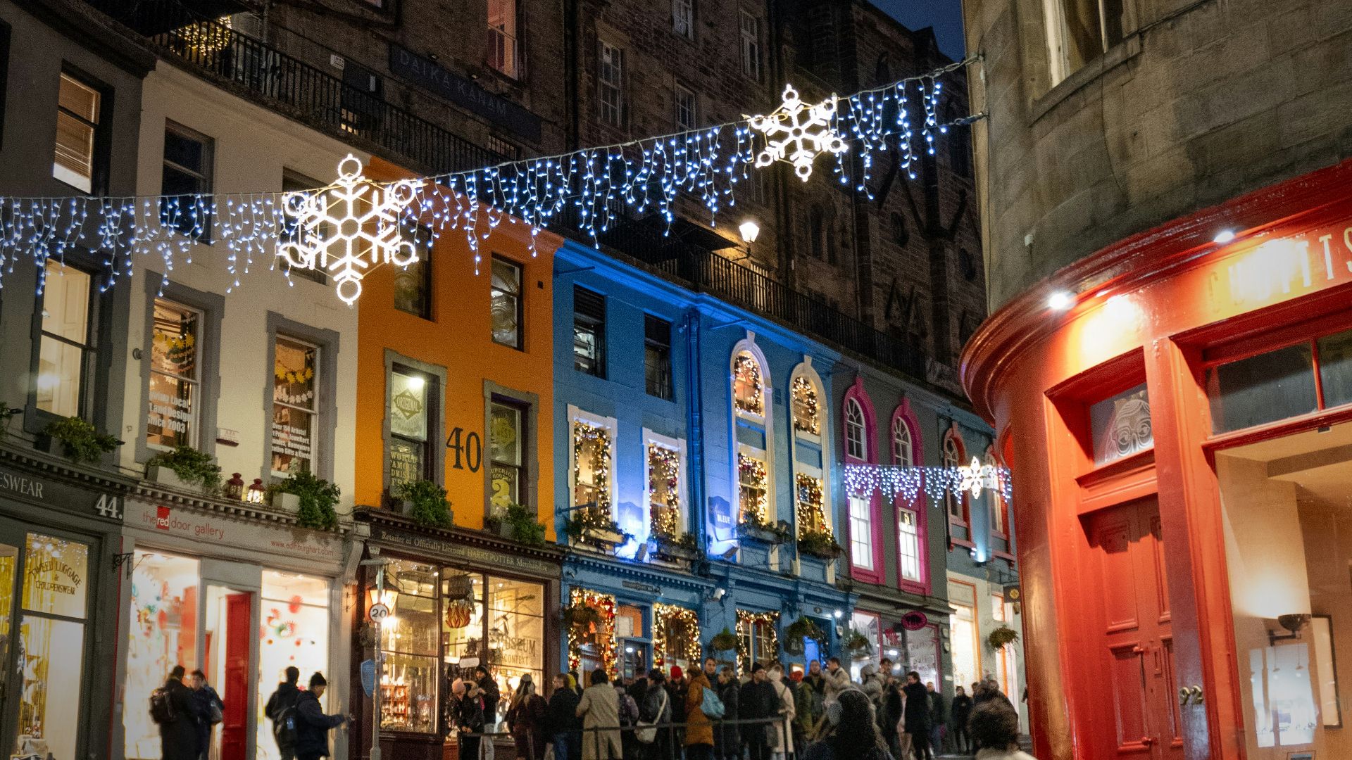 A group of people walking down a street next to tall buildings