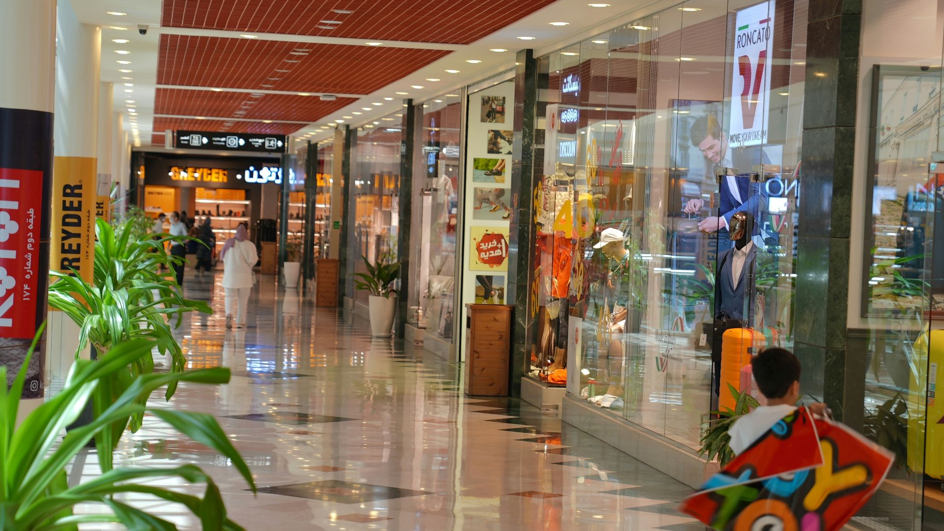 a young boy is holding a toy in a mall