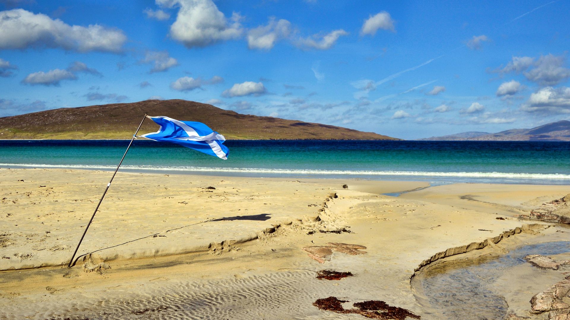 sand near ocean under blue sky