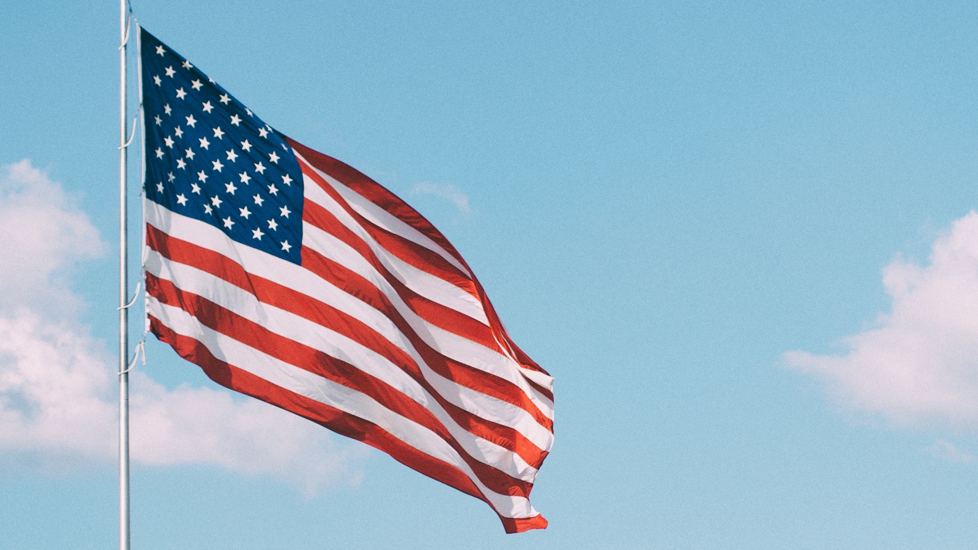 flag of U.S.A. under white clouds during daytime
