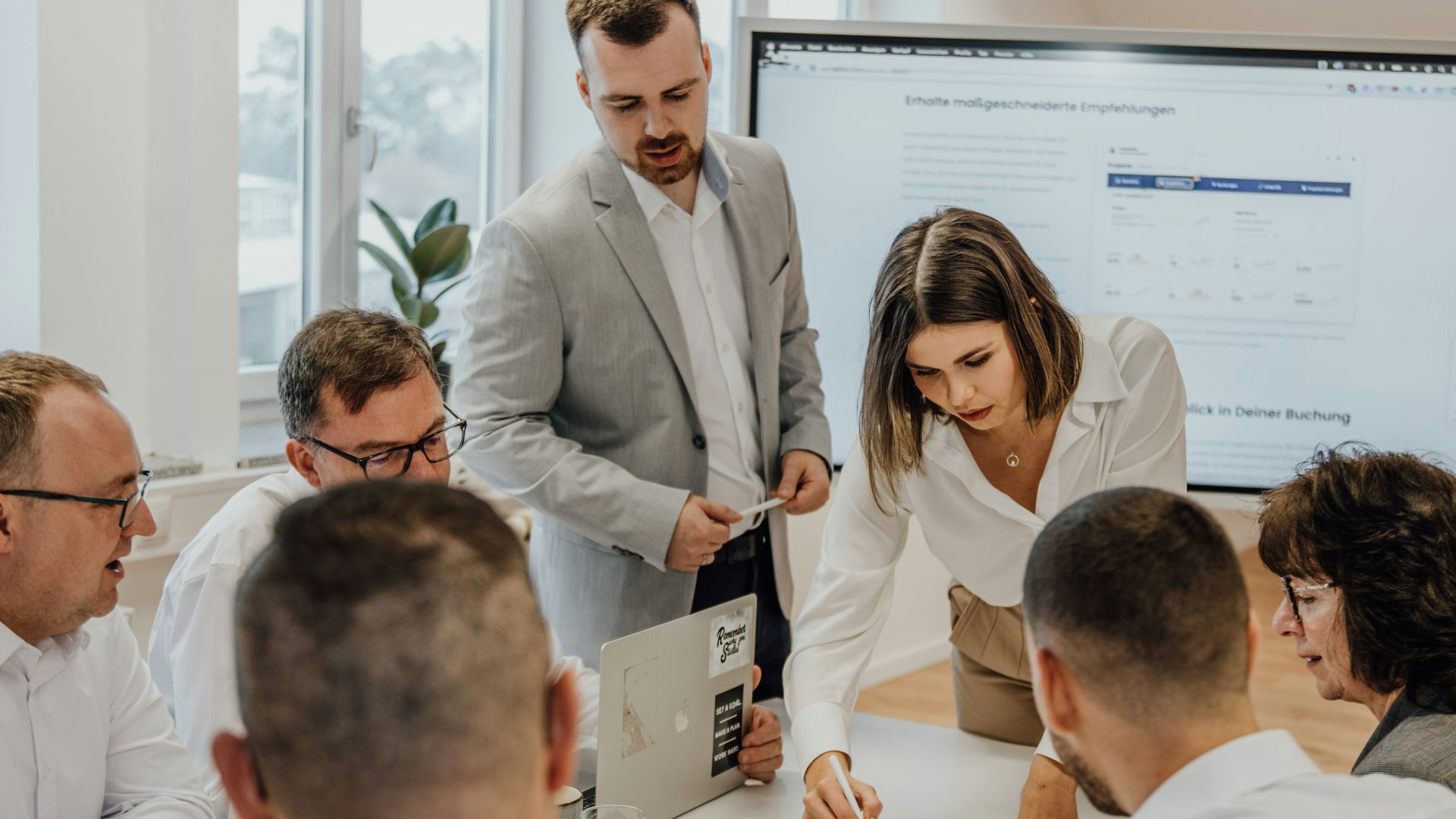 a group of people sitting around a table with laptops