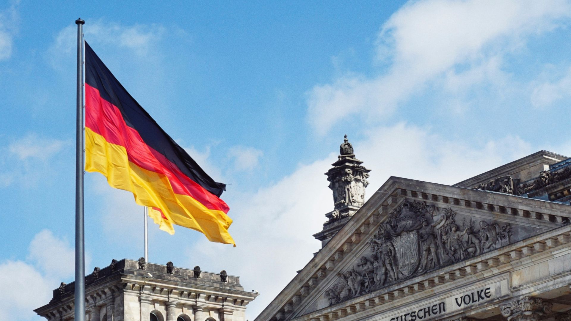 white concrete building with flags on top under blue sky during daytime