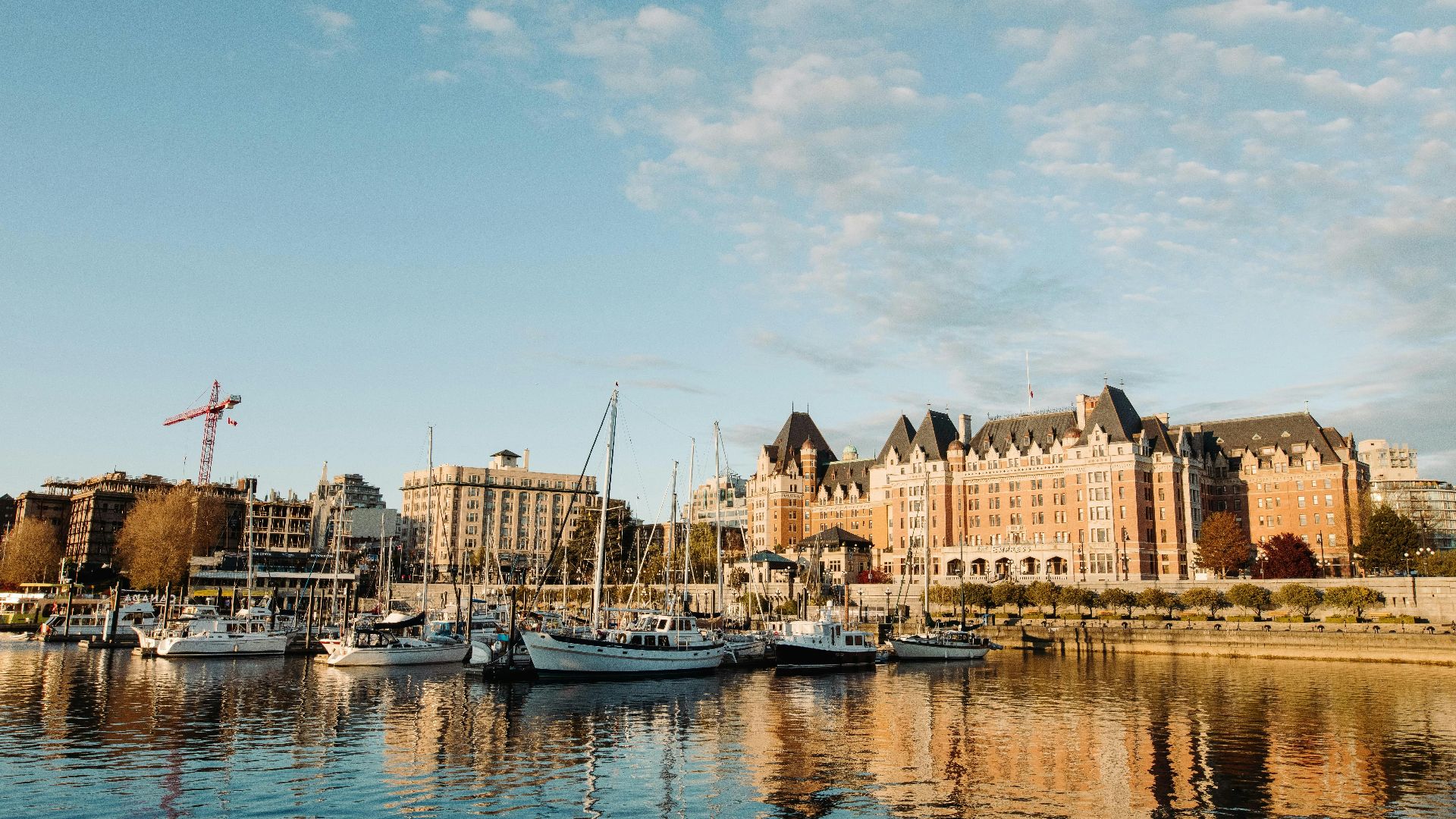 white and blue boat on water near brown concrete building under blue sky during daytime