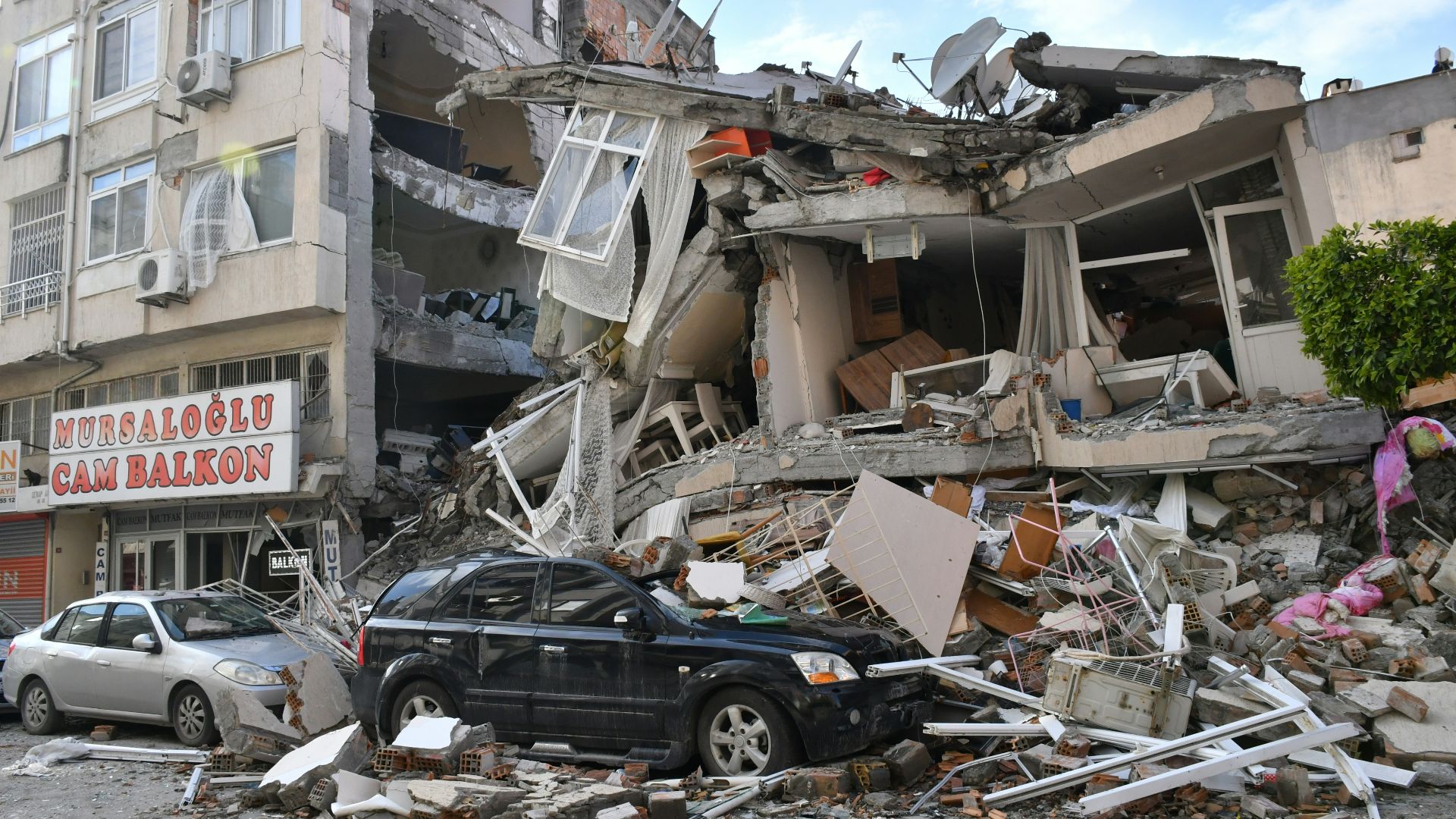 a car is parked in front of a destroyed building