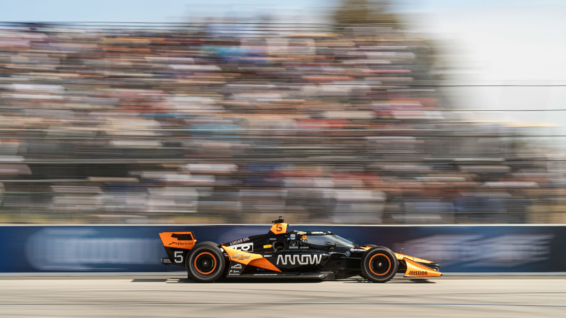 A race car speeds past the blurry crowd.