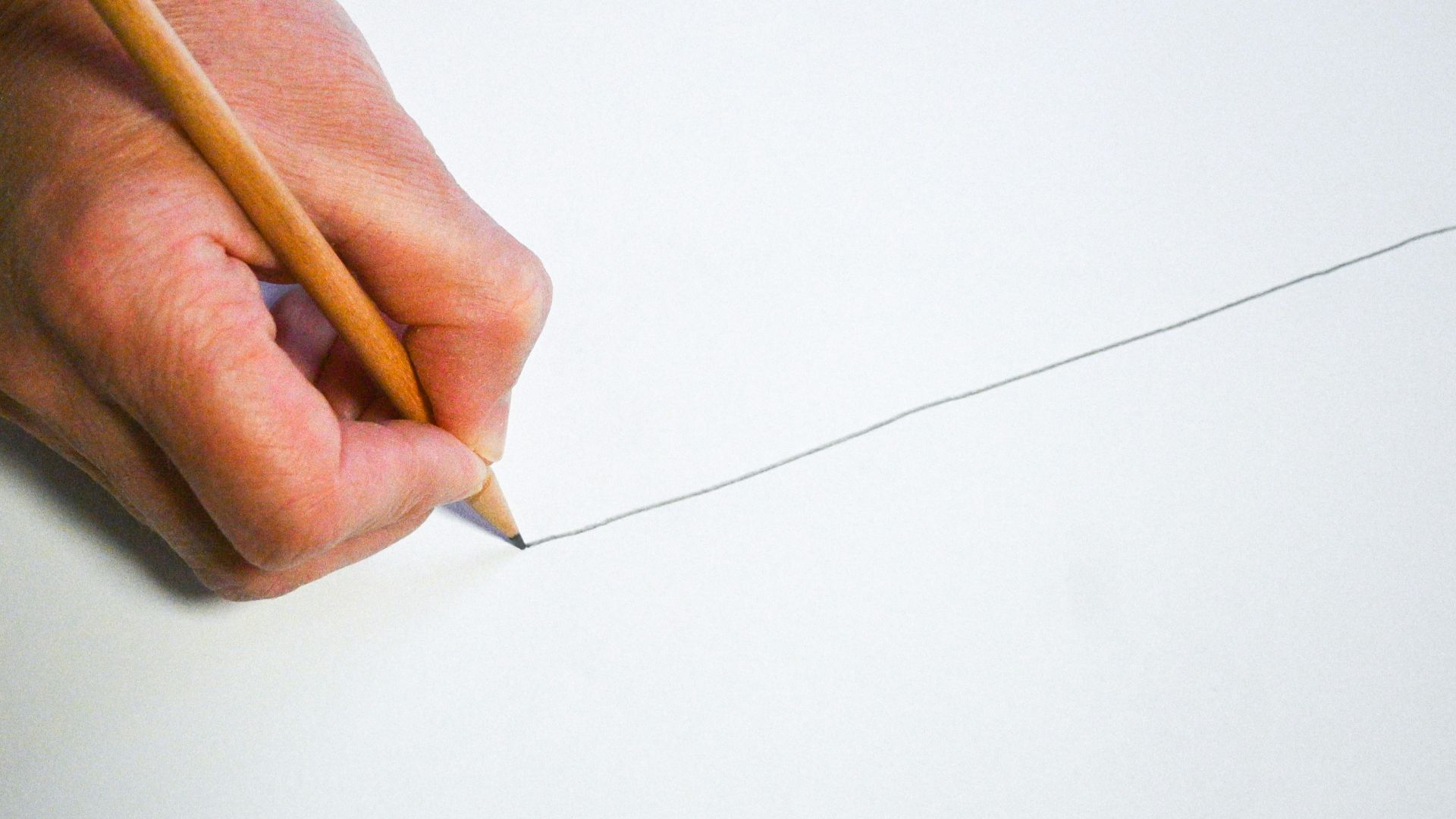 A person holding a pencil and writing on a piece of paper