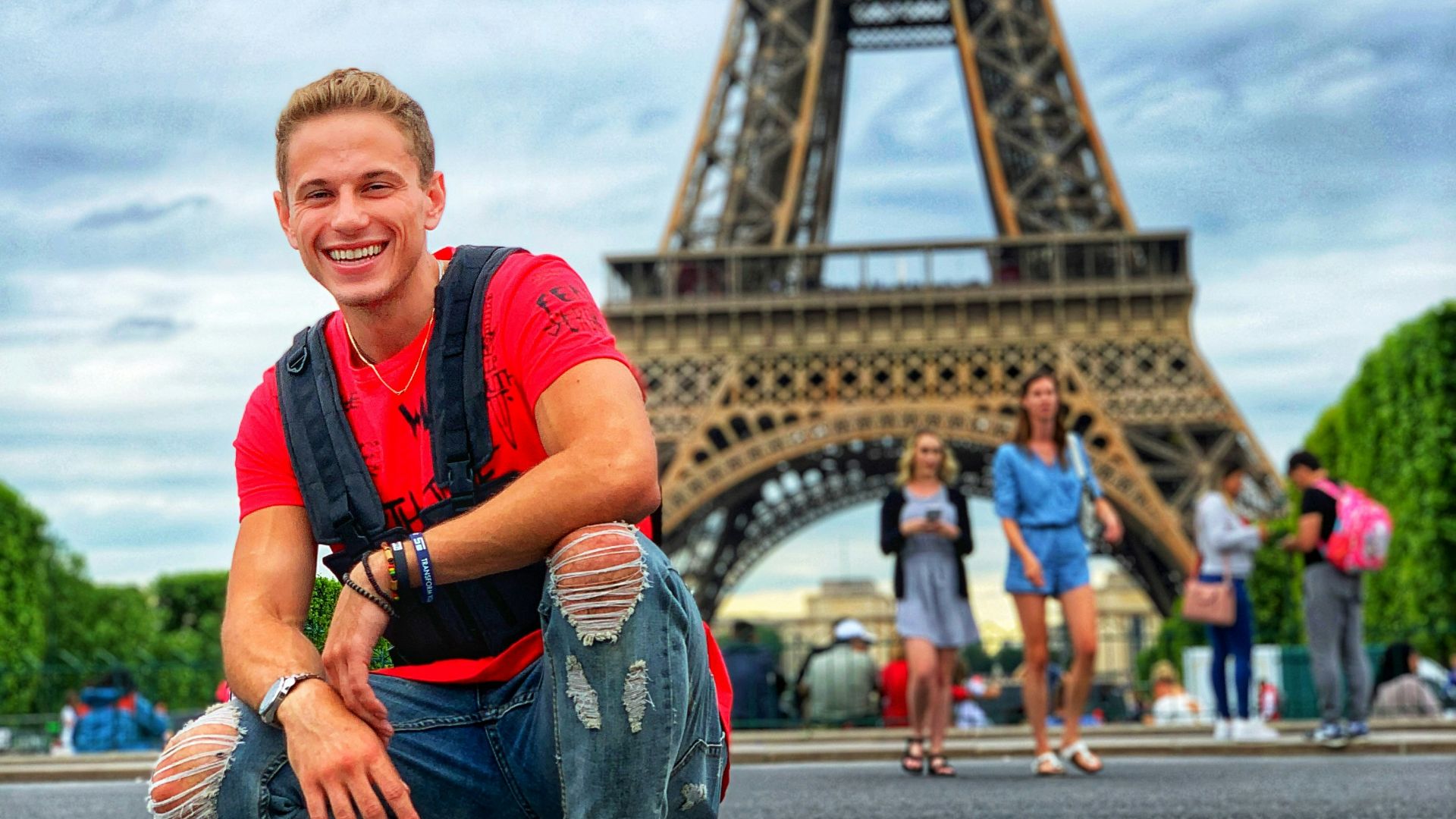 smiling man sitting by group of people near Eiffel tower