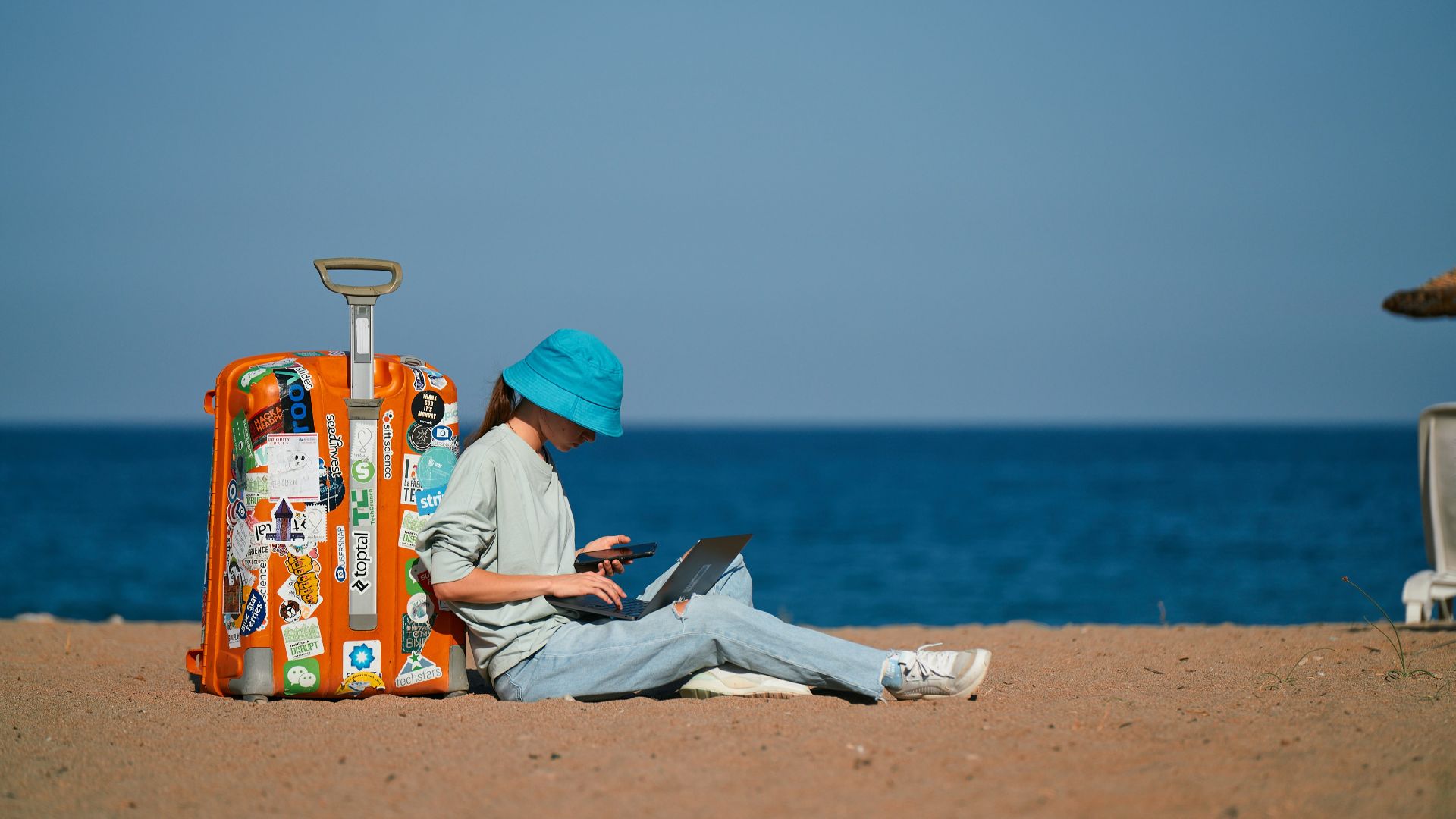 a person sitting on the beach with a suitcase
