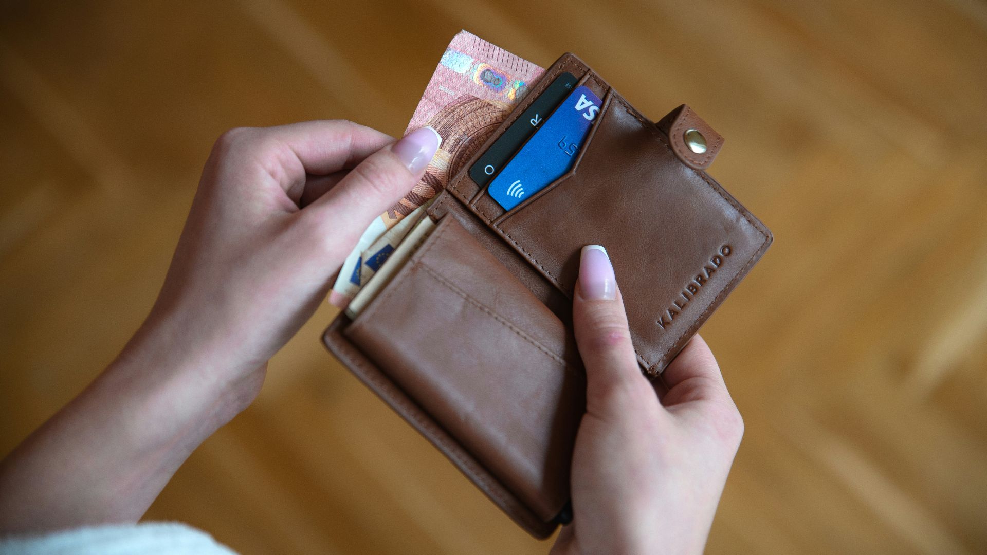 person holding brown leather card wallet