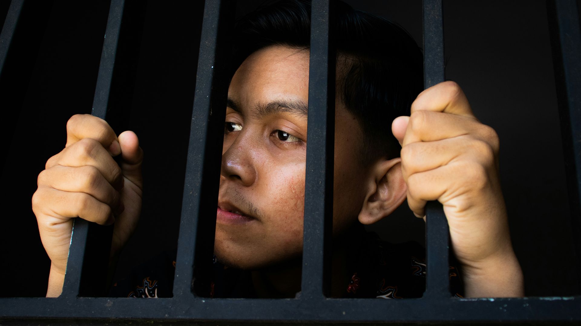 a man is looking out of a jail cell