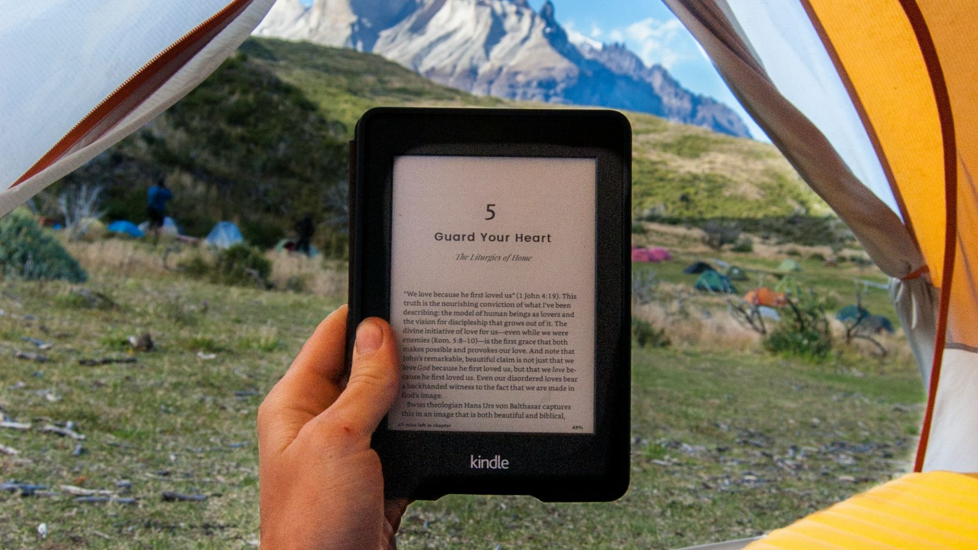 person holding black Amazon Kindle E-Book reader inside tent at daytime