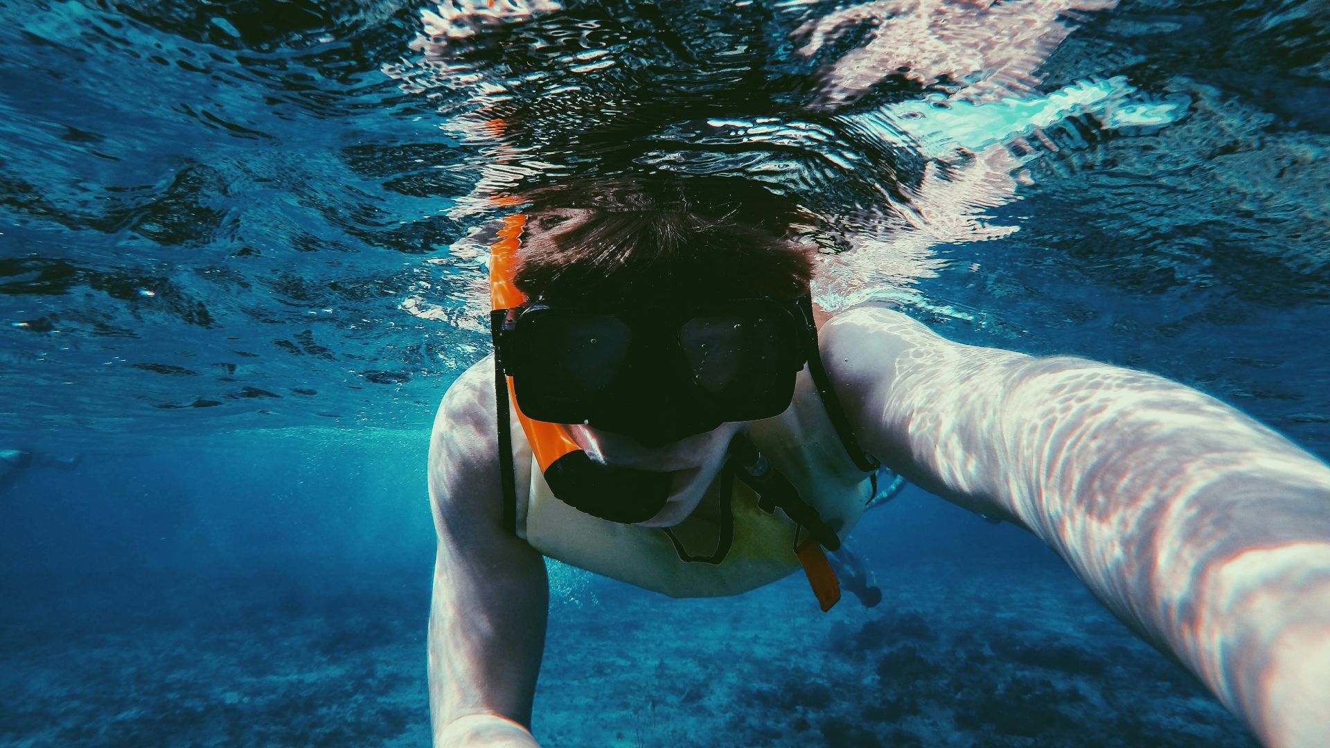 underwater photo of person wearing diving goggles and snorkel