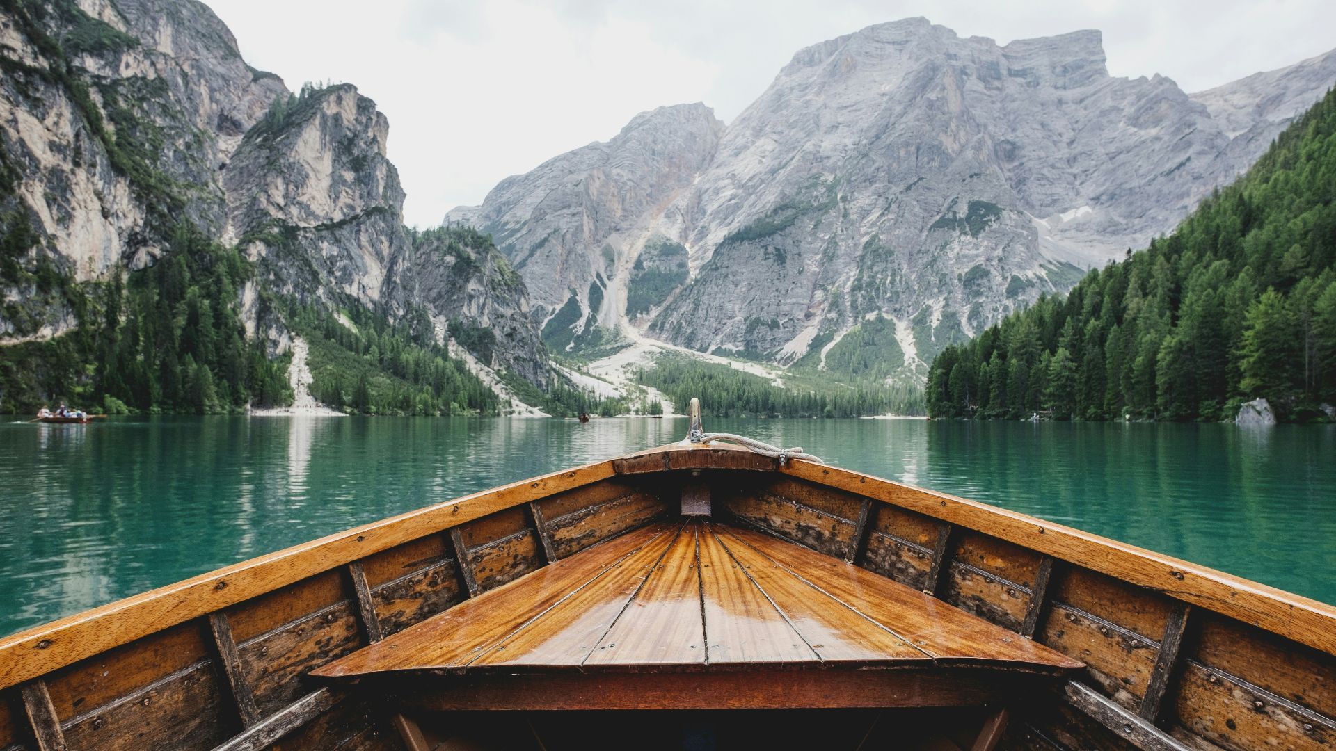 brown wooden boat moving towards the mountain