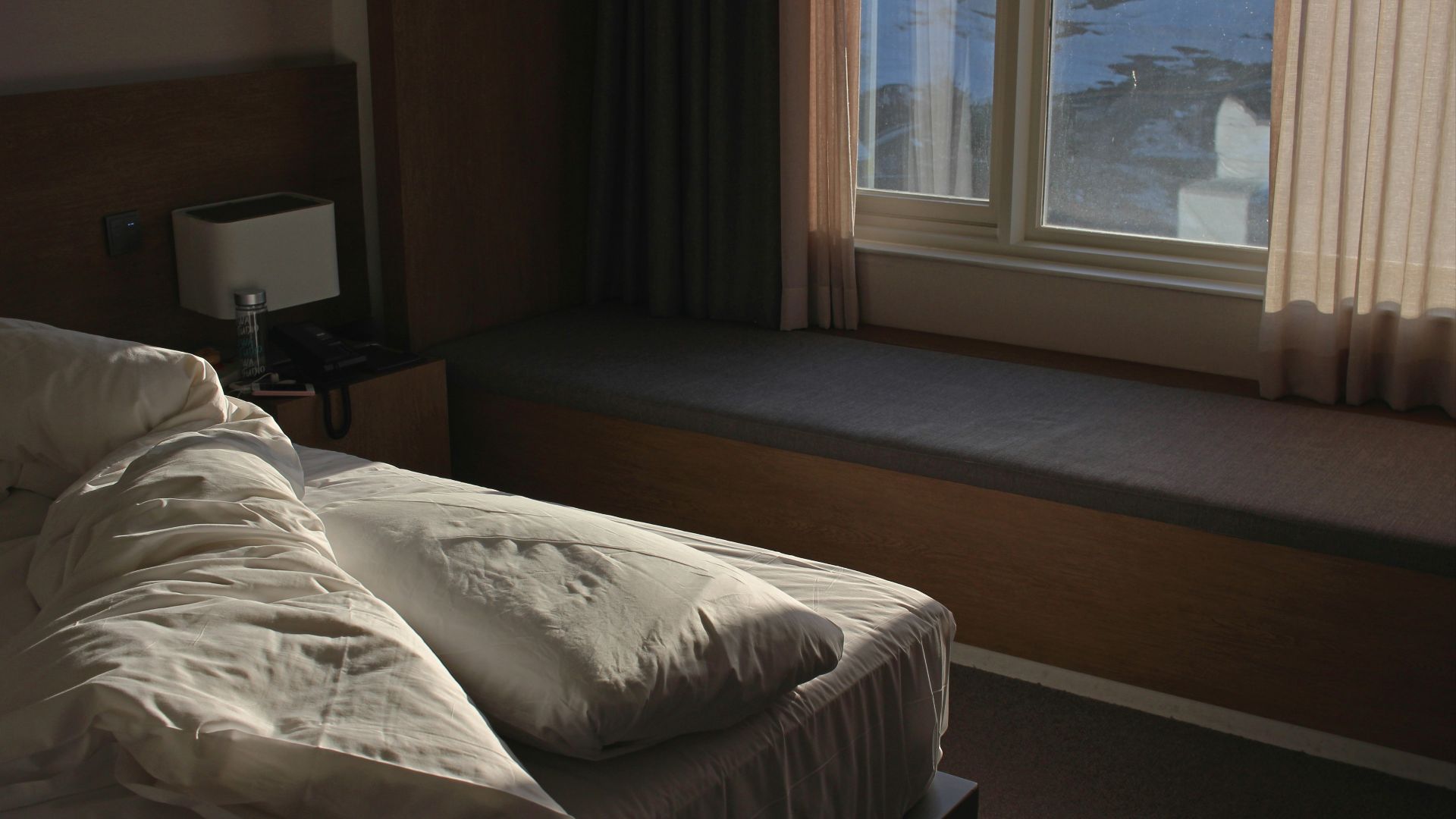 white bed linen near brown window curtain