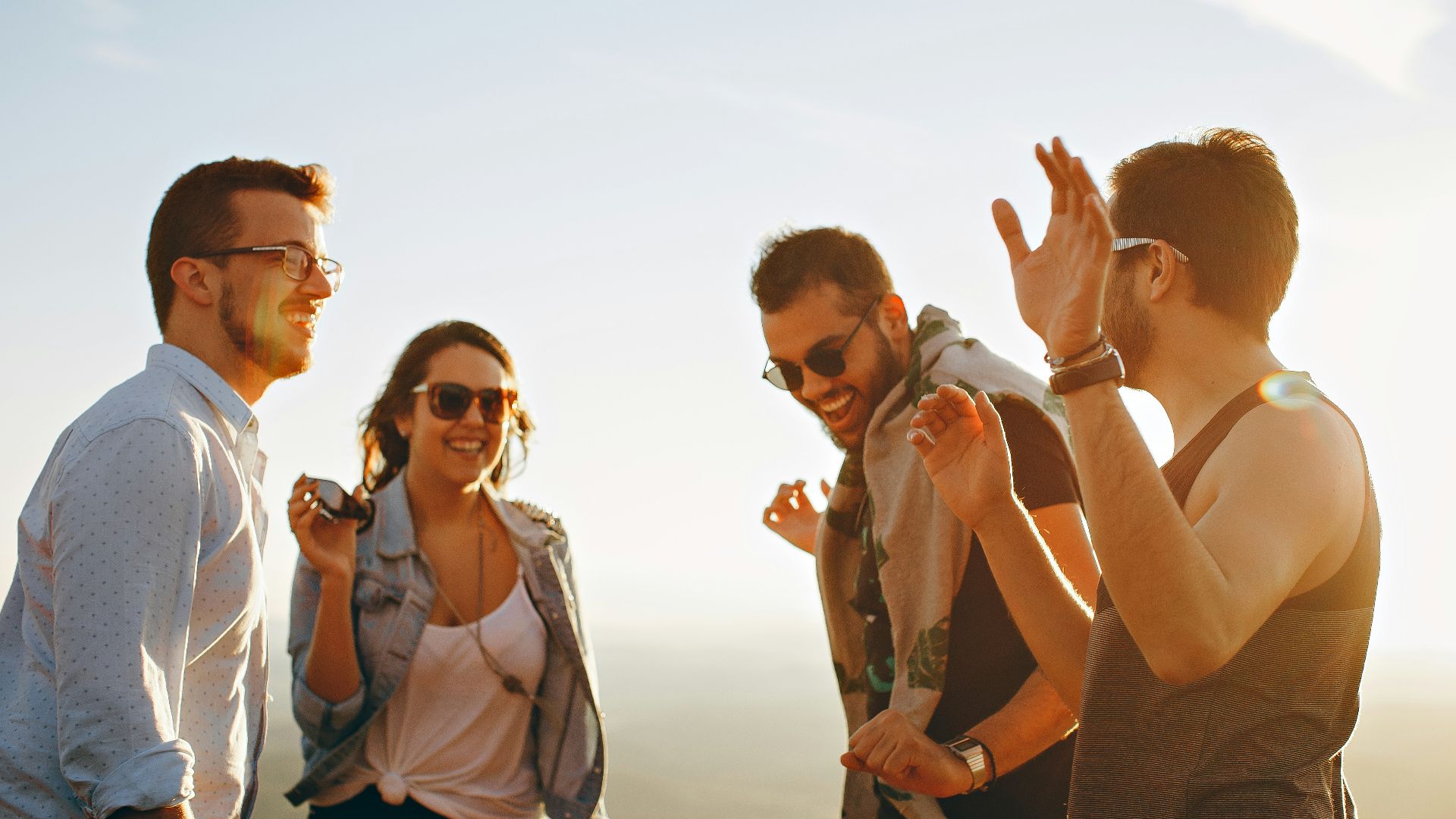 three men and one woman laughing during daytime