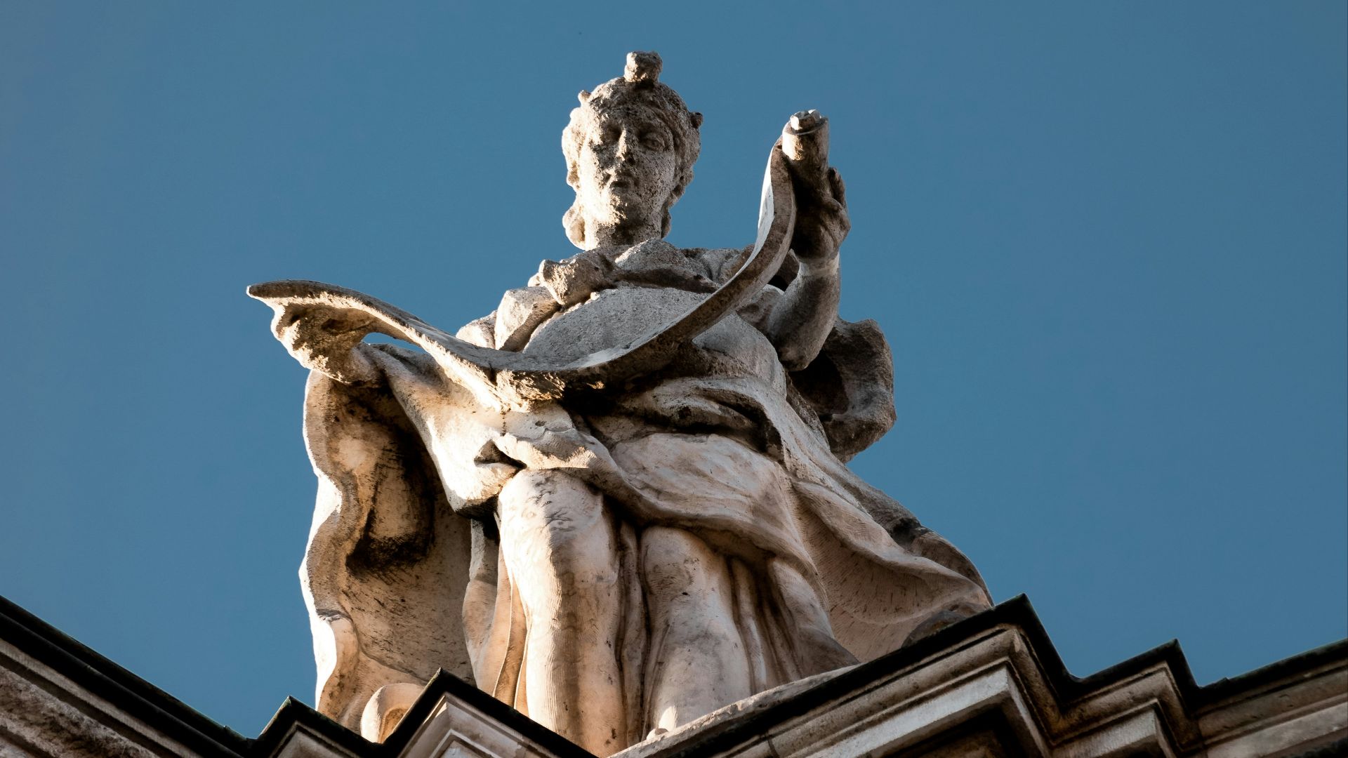 a statue of a woman sitting on top of a building