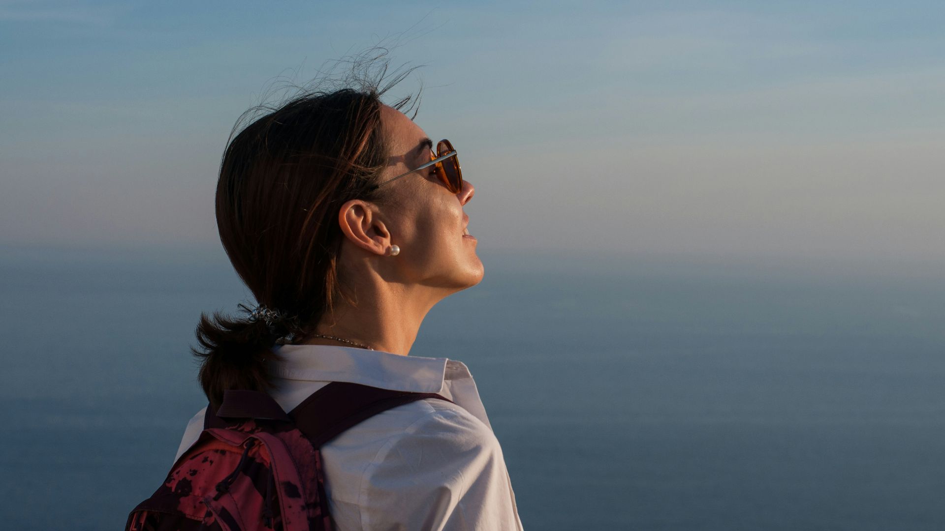 a woman with a backpack looking at the ocean