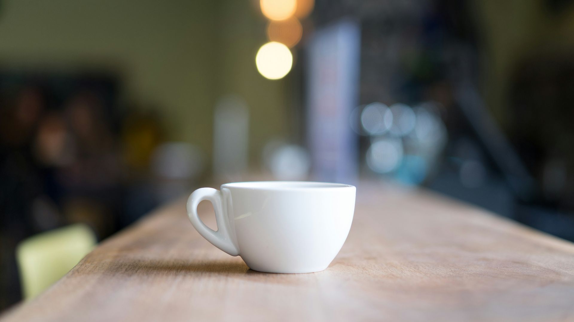 bokeh photography of white mug on brown table