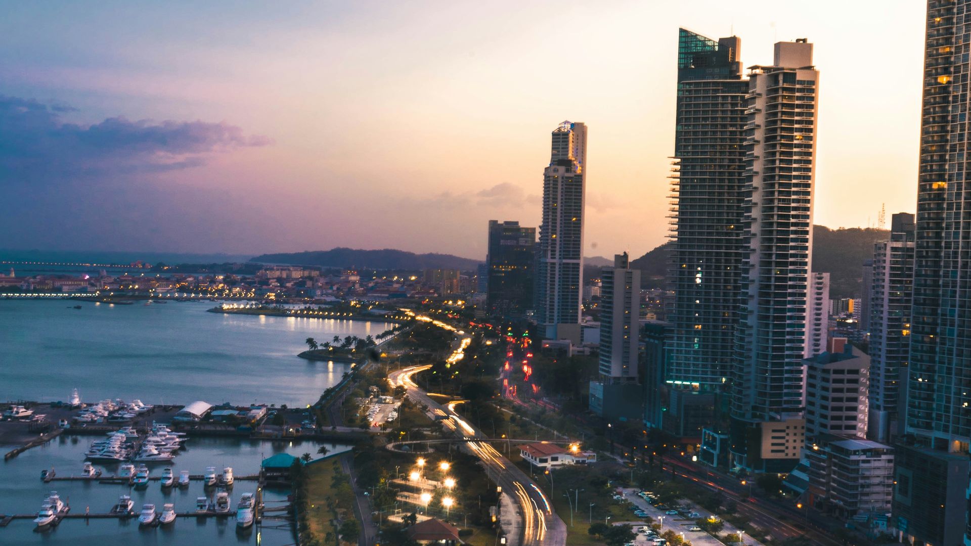 high rise buildings near body of water in distant of mountain