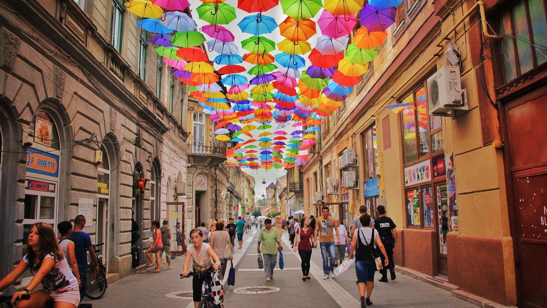 assorted-color umbrella hanged above pathway near houses