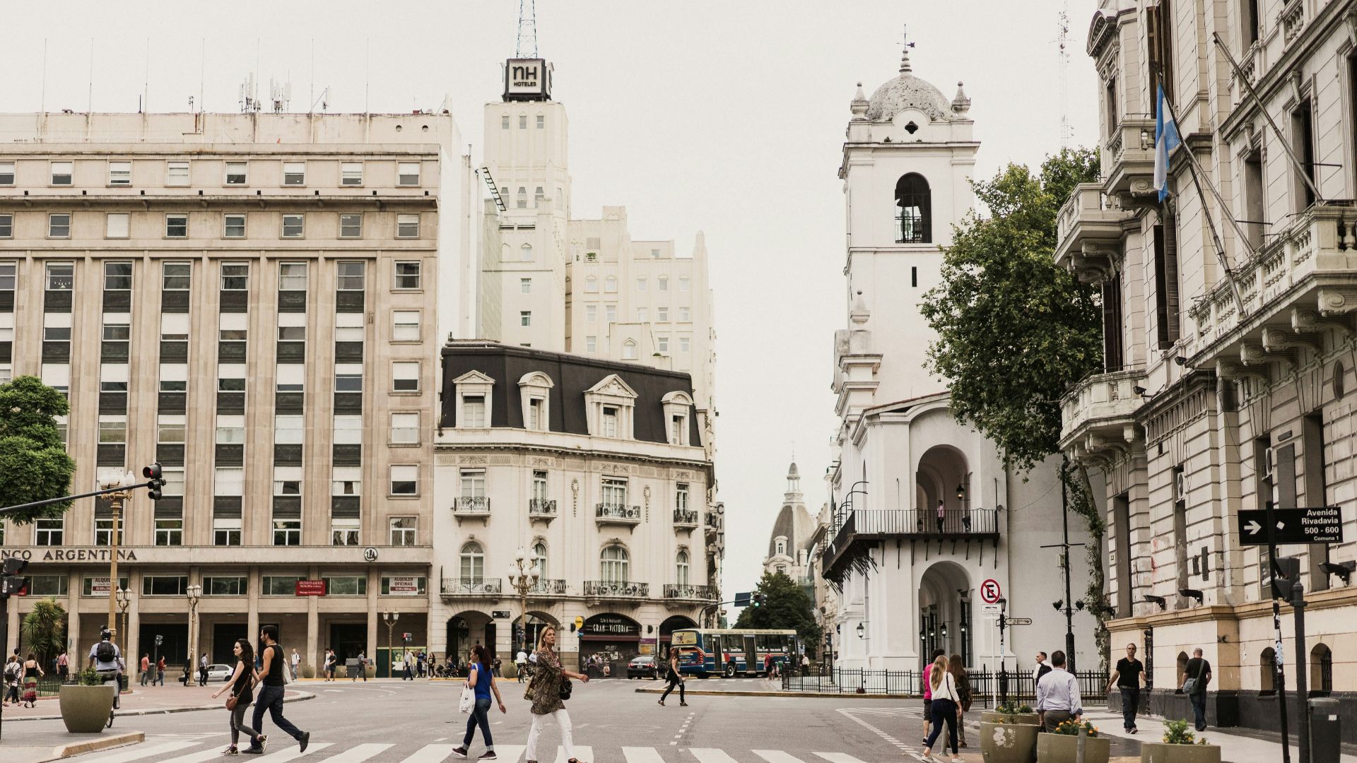 woman crossing pedestrian lane between tall buildings