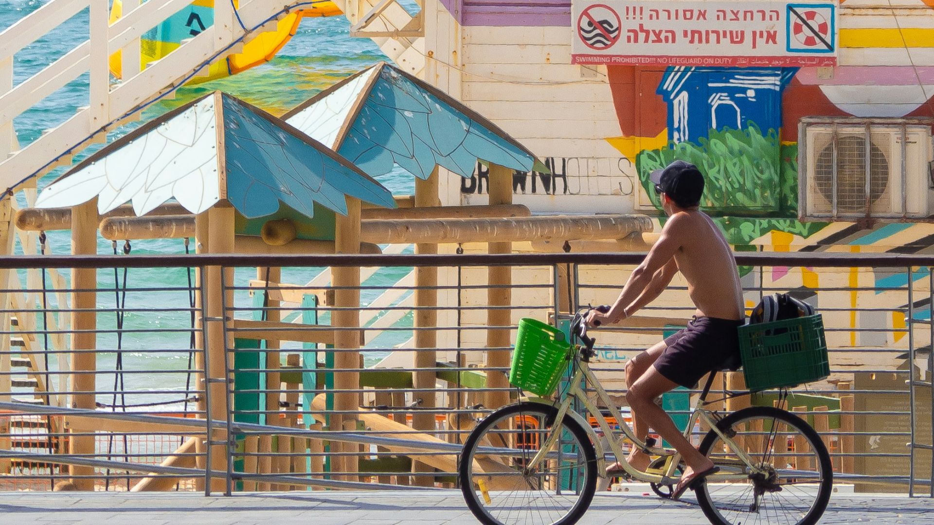 man in green shirt riding on bicycle near body of water during daytime