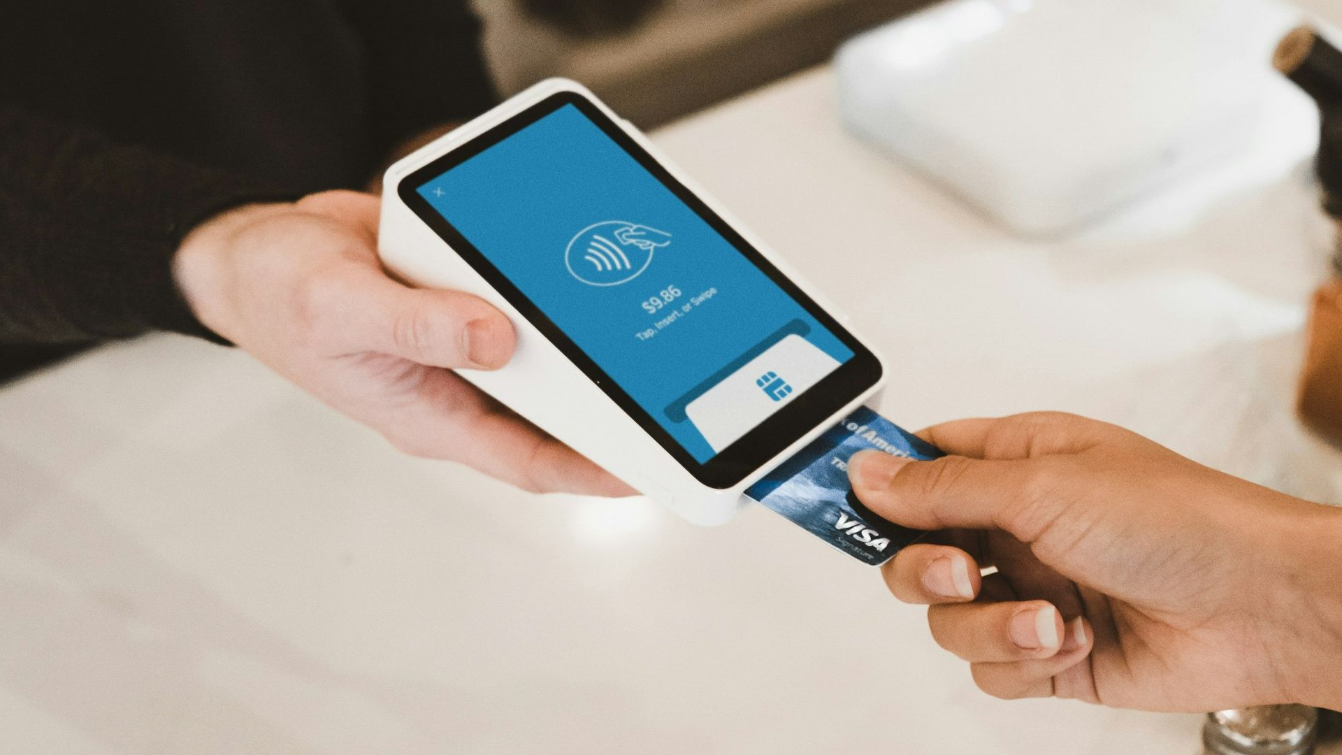 person putting magstripe card near black card terminal