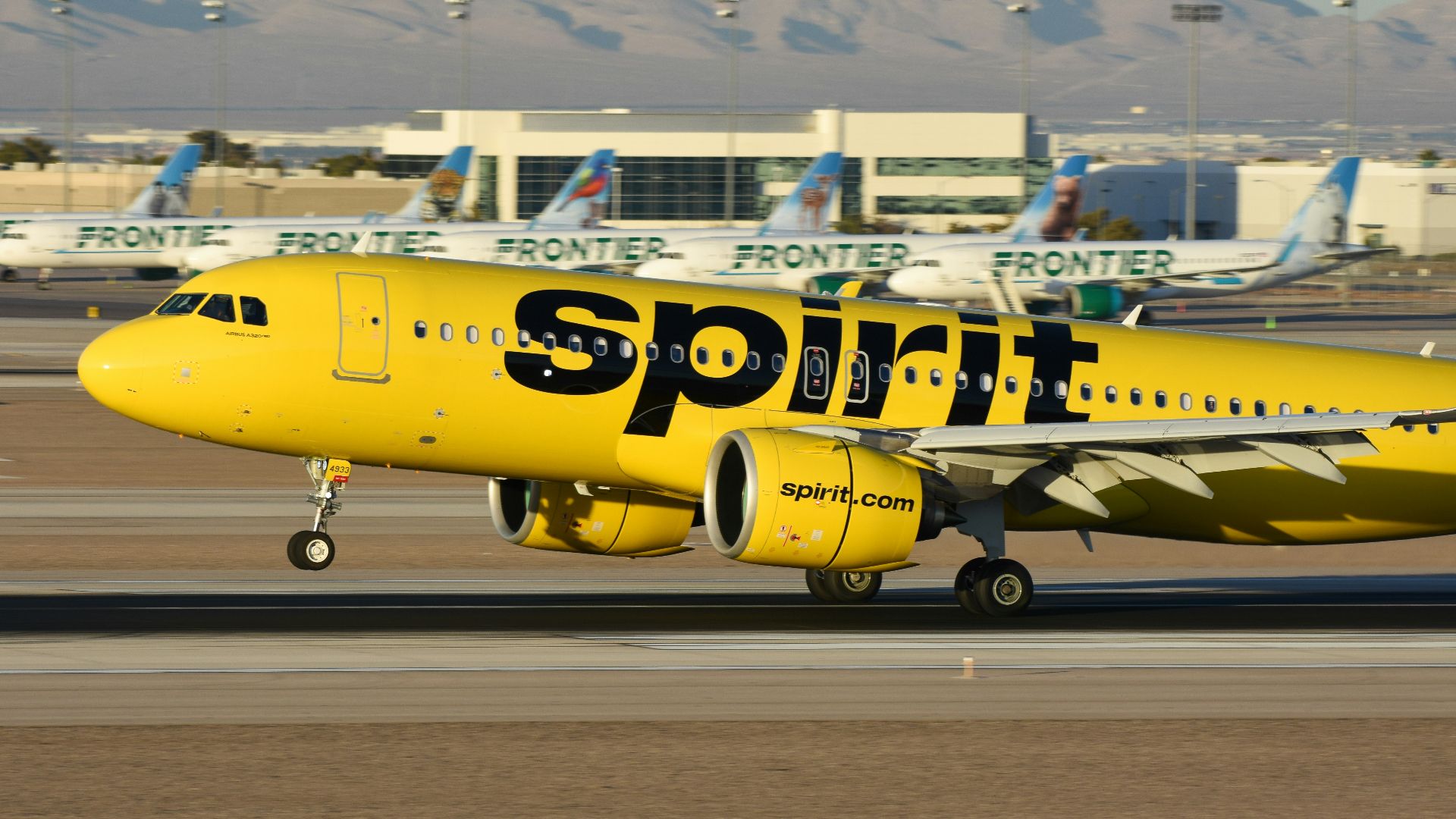 A yellow spirit airplane on the runway of an airport
