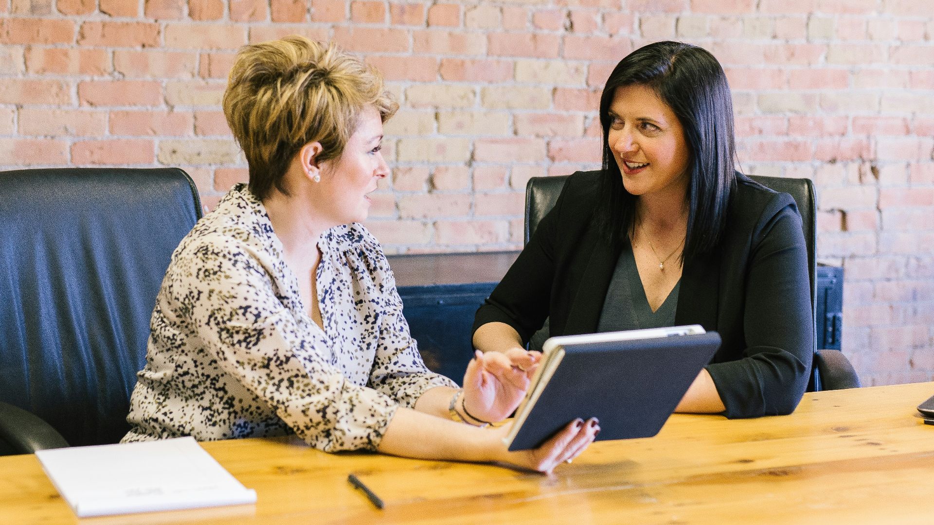 two women sitting on leather chairs in front of table