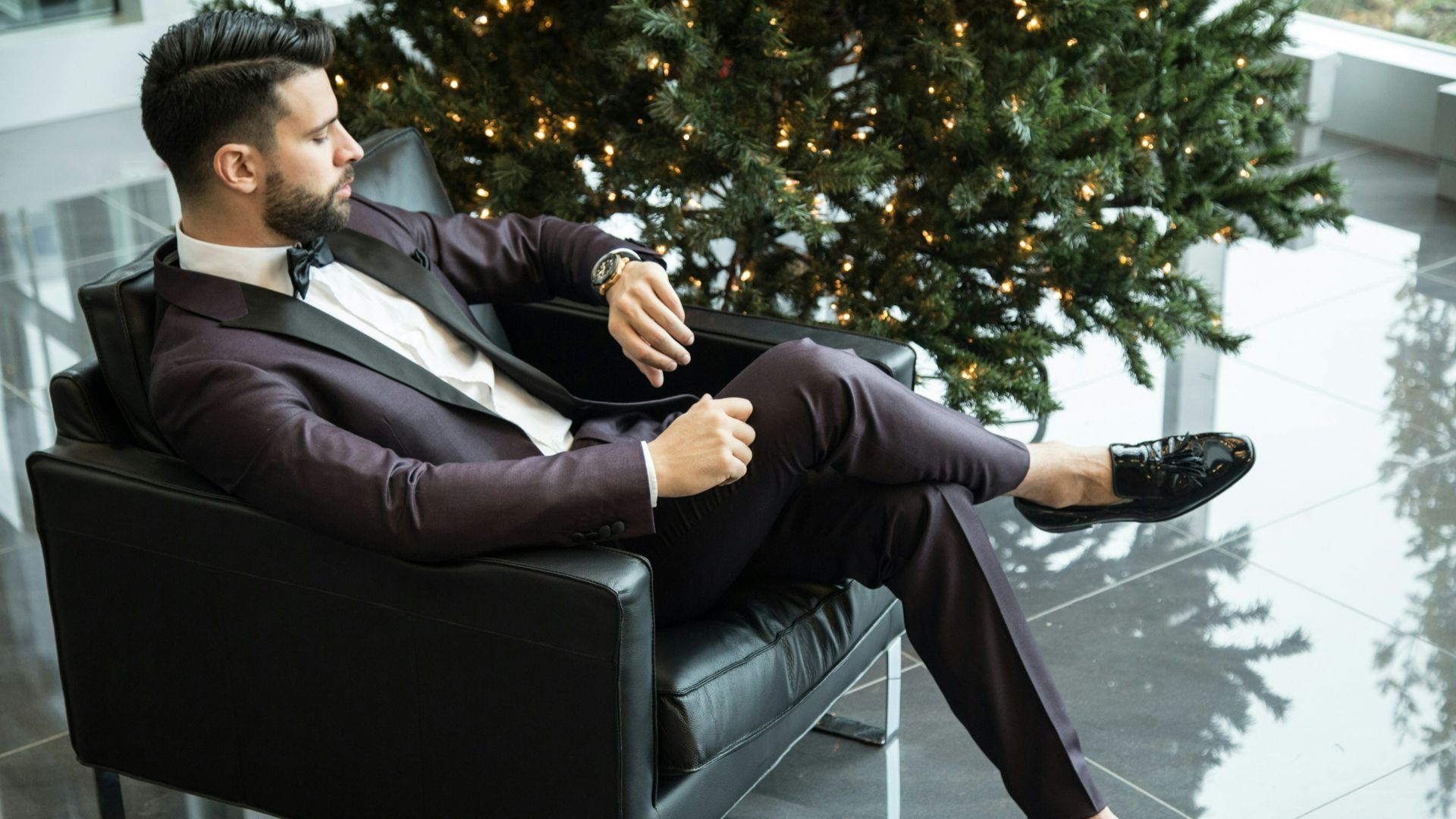 man sitting on black sofa chair while watching watch