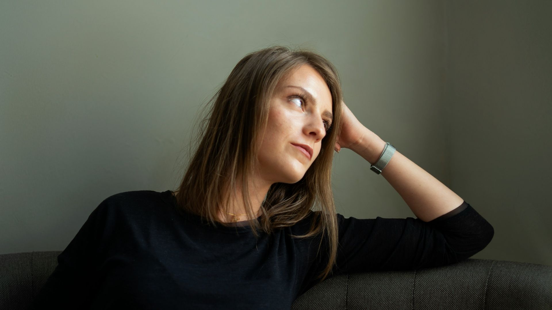 woman in black crew neck t-shirt holding green ceramic mug sitting on black sofa