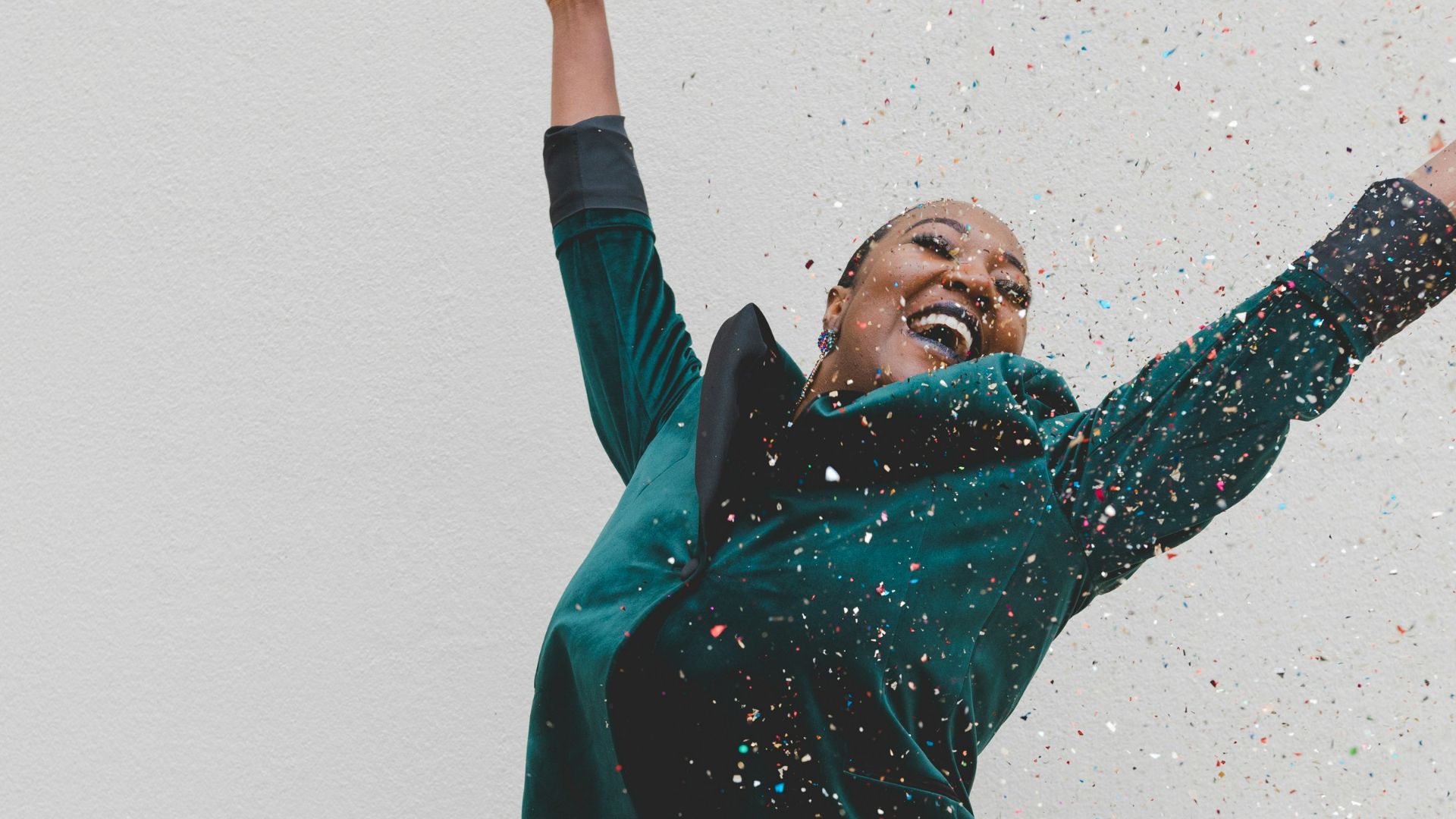 woman in green jacket raising her hands