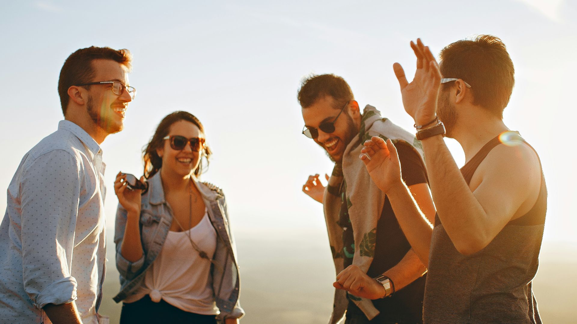 three men and one woman laughing during daytime