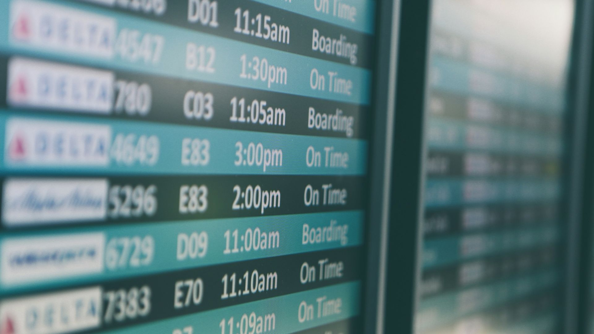 Airport departures timetable showing Delta and Alaska Airlines flights on time and boarding