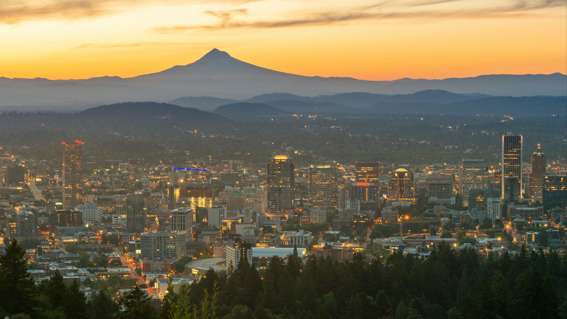city with high rise buildings near mountain during sunset
